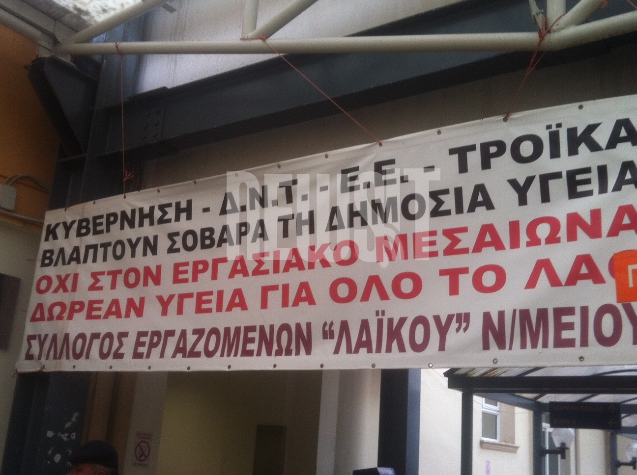 Κυβέρνηση - ΔΝΤ - Ε.Ε - Τρόϊκα βλάπτουν σοβαρά την υγεία λέει το πανό που έχουν αναρτήσει στην είσοδο του Λαϊκού Νοσοκομείου οι εργαζόμενοι 