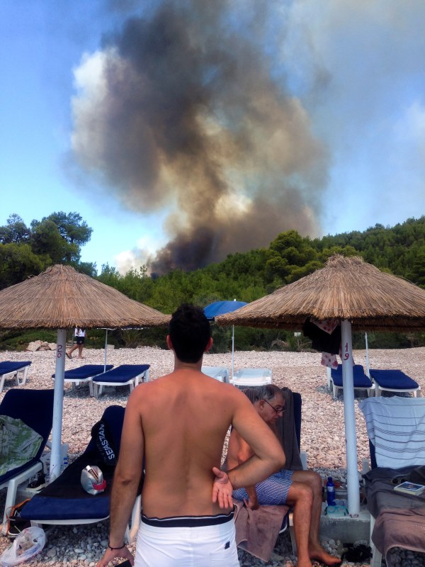 Άνθρωποι βλέπουν τη μεγάλη φωτιά από παραλία του νησιού - ΦΩΤΟ REUTERS