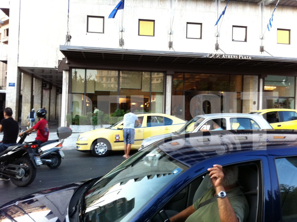 Τι περιμένει άραγε ο κύριος με το ταξί του έξω από το ξενοδοχείο; Επίσης, το κίτρινο όχημα πίσω από το ταξί φέρει την μπλέ γραμμή;