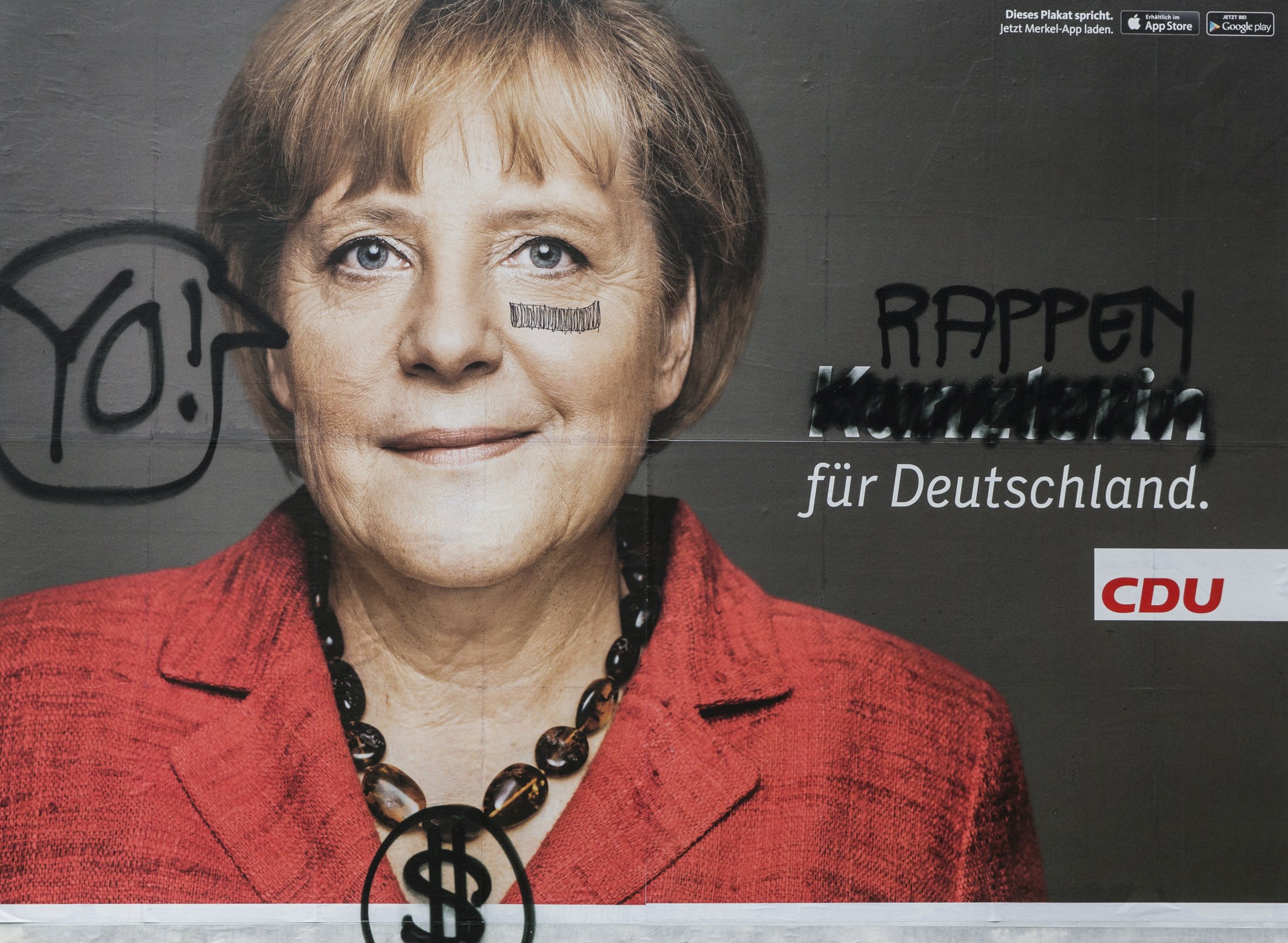 Και η αφίσα της Άνγκελα Μέρκελ: το τσιρότο, το σήμα του δολαρίου σαν κολιέ και η καγκελάριος που... ραπάρει για τη Γερμανία