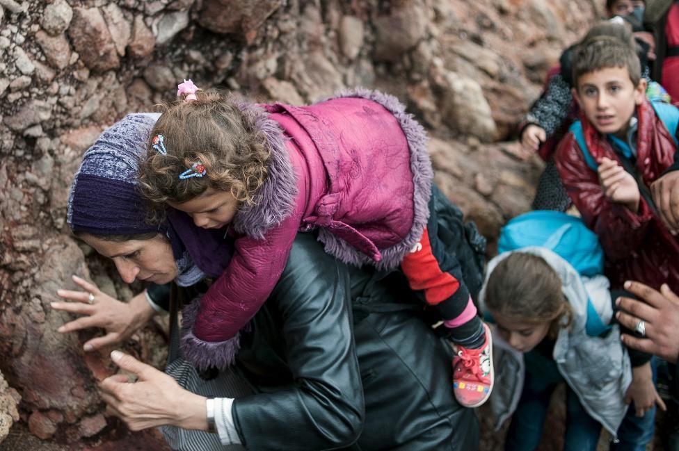 15. Λέσβος, Κυριακή 11 Οκτωβρίου Μια γυναίκα πρόσφυγας μεταφέρει το παιδί της λίγο μετά την άφιξή της σε βραχώδη παραλία της Λέσβου και αφού πέρασε στο Αιγαίο από τις τουρκικές ακτές