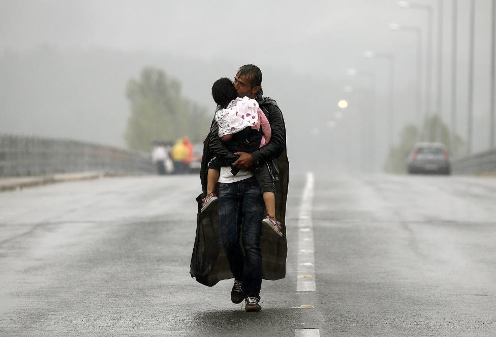 69. Ειδομένη, Πέμπτη 30 Σεπτεμβρίου Ένας Σύρος πρόσφυγας φιλά την κόρη του καθώς περπατά στη βροχή προς τα σύνορα της Ελλάδας με την ΠΓΔΜ κοντά στην Ειδομένη. 