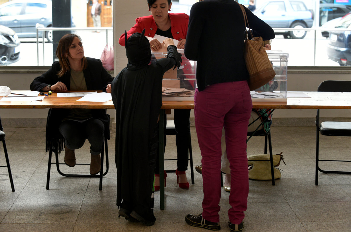 Ένας μπόμπιρας ντυμένος Μπάτμαν ρίχνει το ψηφοδέλτιο της μητέρας του στην καλπη