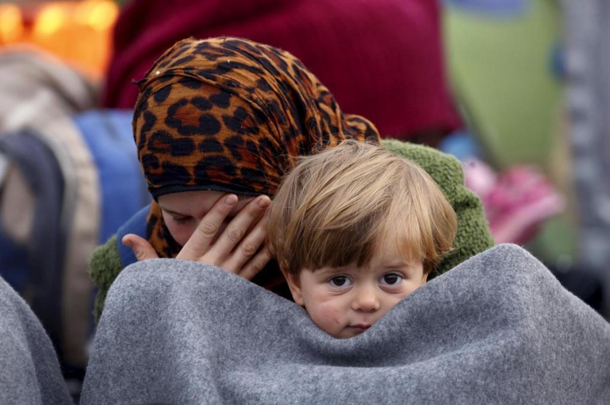 Μια μητέρα με το παιδί της περιμένει να ανοίξουν τα σύνορα - ΦΩΤΟ REUTERS