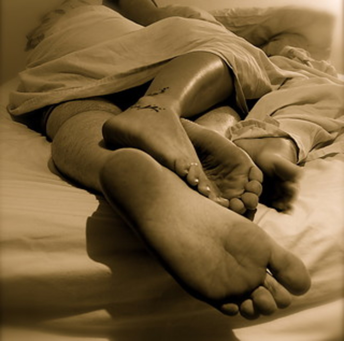 Девушка обнимает ногу. Сплетение ног. Переплетение ног. Переплетение ног на кровати. Влюбленные ноги.