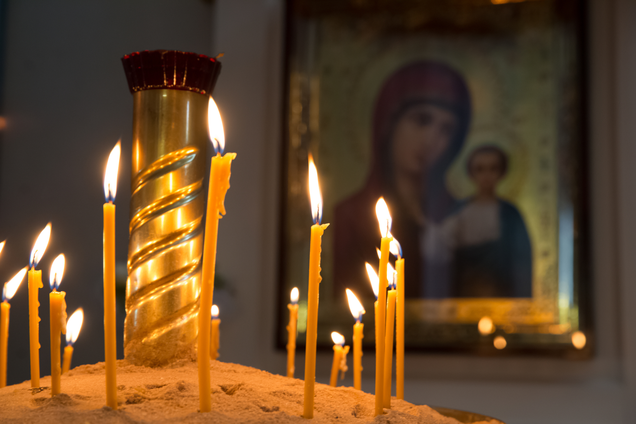 Prayer candles. Candleholder in the Russian Orthodox Christian Church. Blurred image of The Virgin and child is on background.