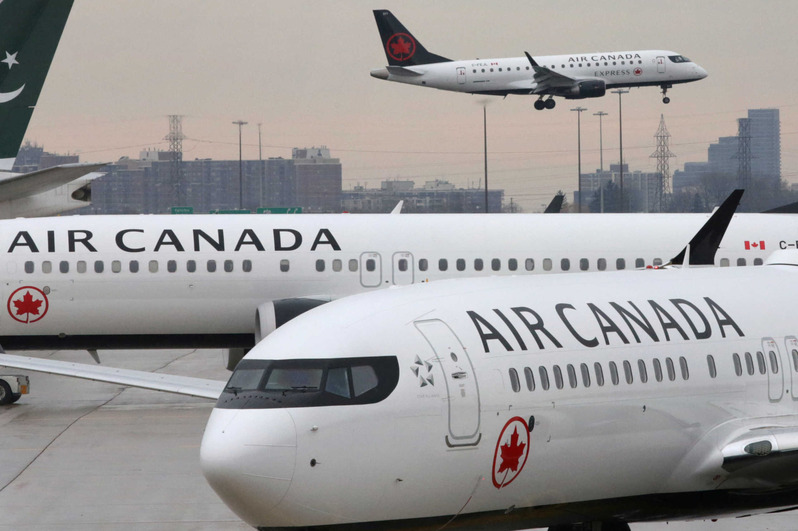 FILE PHOTO: Two Air Canada Boeing 737 MAX 8 aircrafts are seen on the ground as Air Canada Embraer aircraft flies in the background at Toronto Pearson International Airport in Toronto, Ontario, Canada, March 13, 2019.  REUTERS