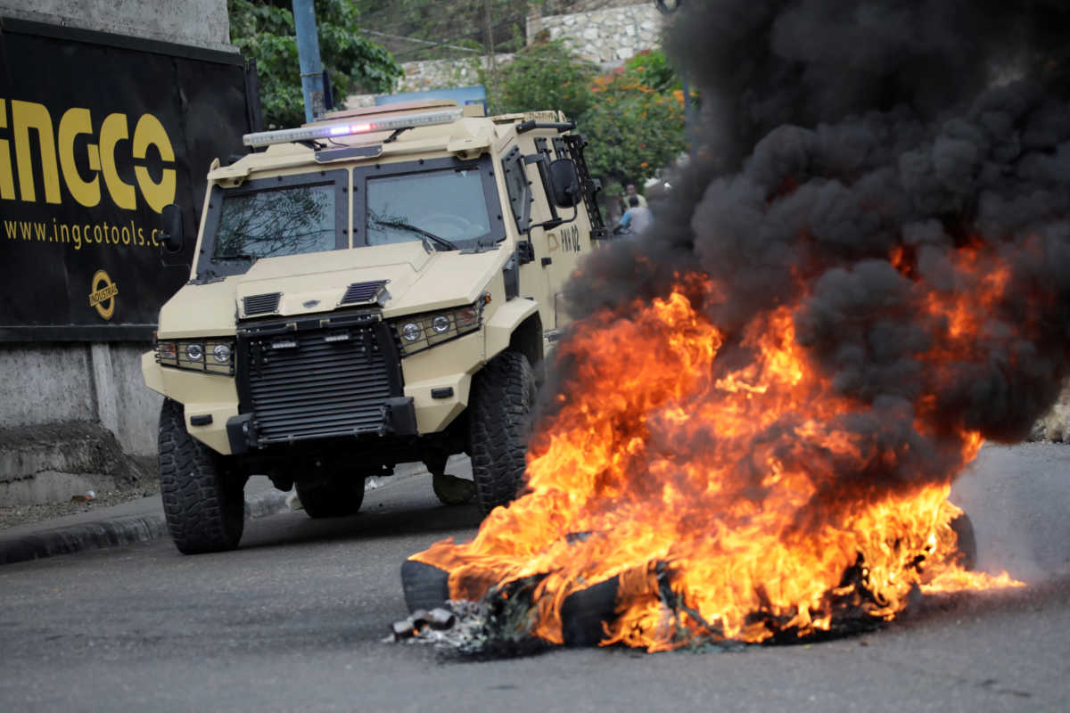 Security forces pass next to fire set by demonstrators during a protest in Port-au-Prince, Haiti February 24, 2020. REUTERS