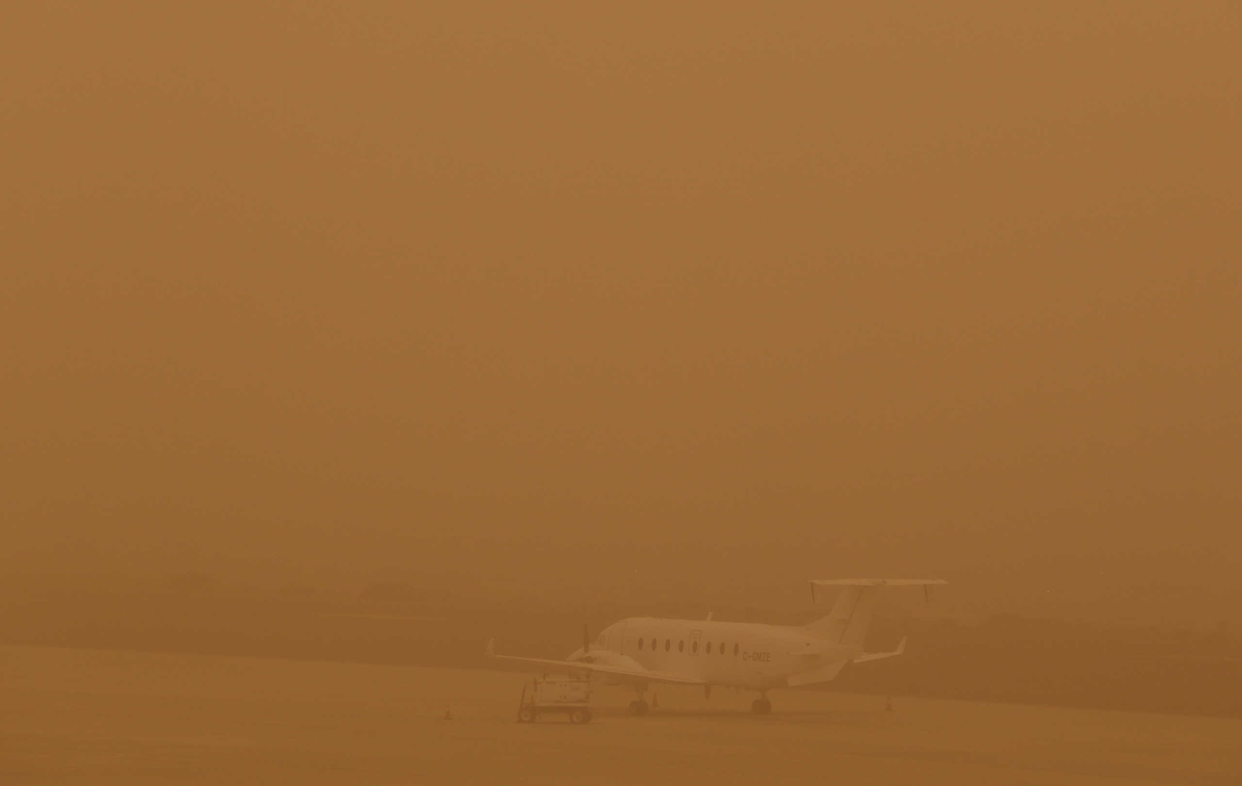 A plane is seen parked on a tarmac during a sandstorm blown over from North Africa known as "calima" at Las Palmas Airport, Canary Islands, Gran Canaria, February 22, 2020. REUTERS