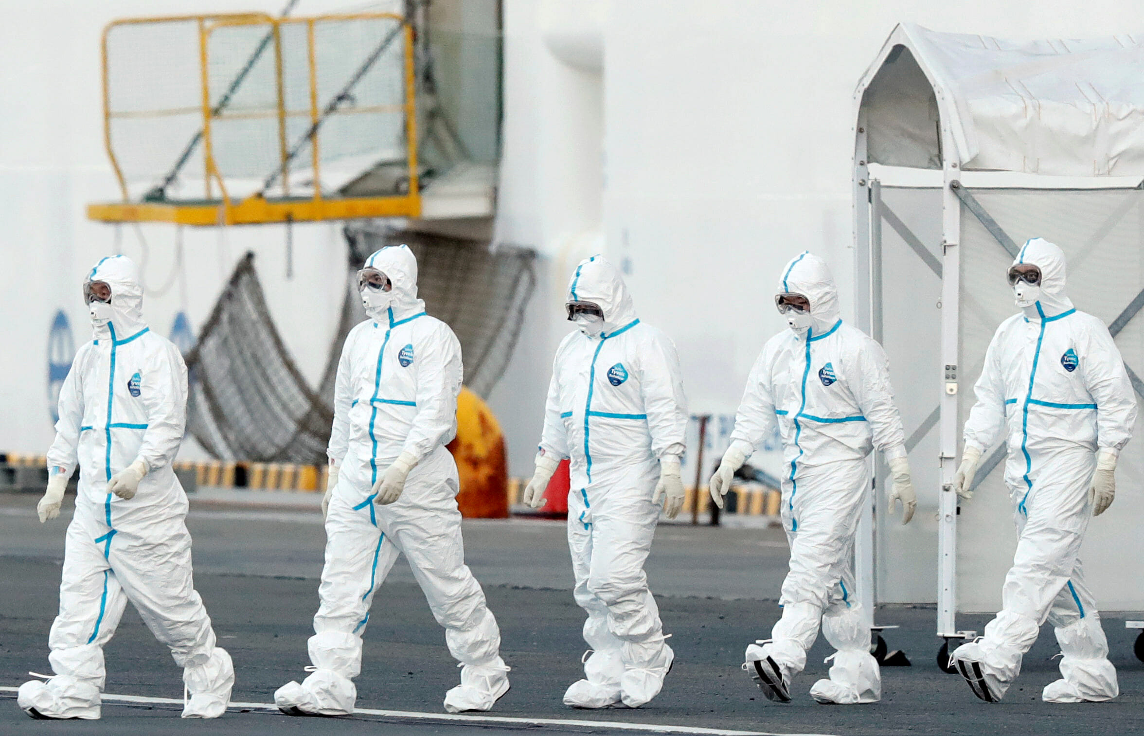 FILE PHOTO: Workers wearing protective suits walk away from the cruise ship Diamond Princess, as they prepare to transfer passengers tested positive for the novel coronavirus, at Daikoku Pier Cruise Terminal in Yokohama, south of Tokyo, Japan February 10, 2020. REUTERS