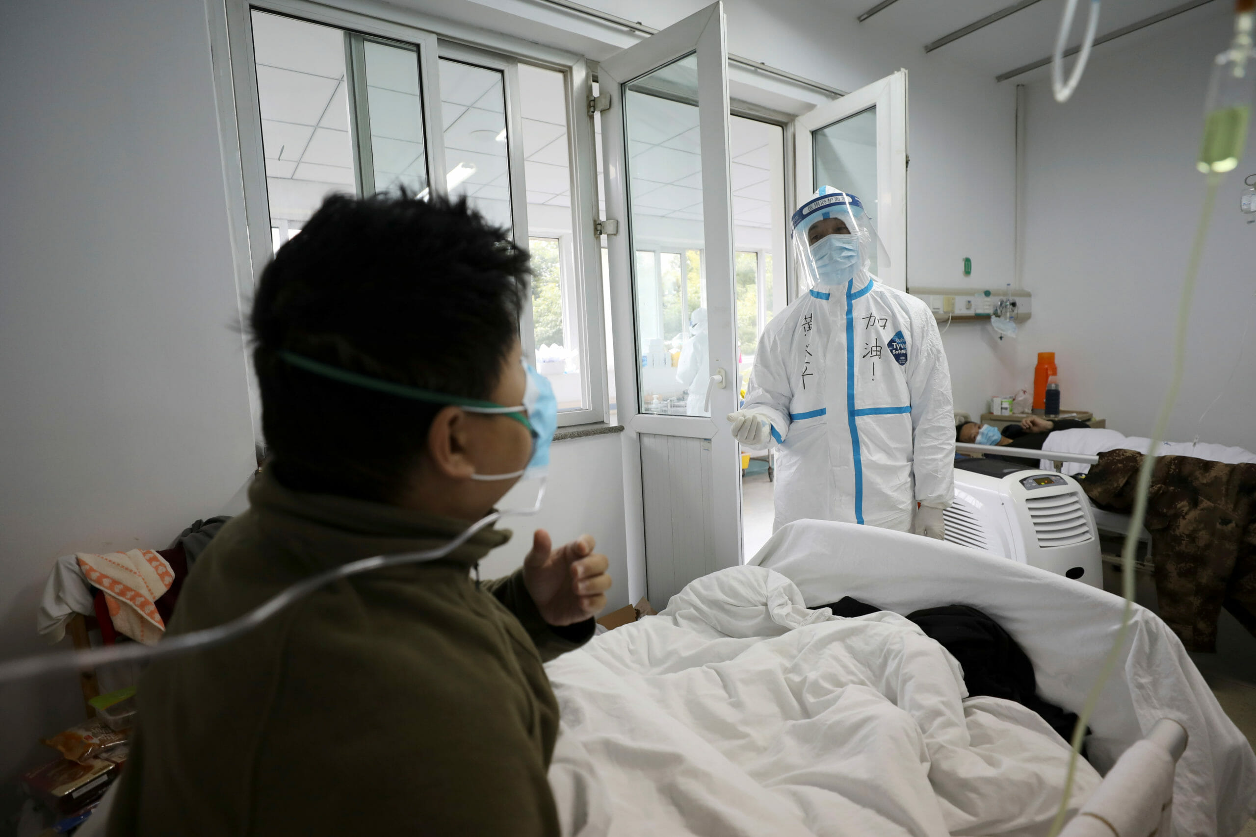 A medical worker in protective suit interacts with a patient inside an isolated ward at Jinyintan Hospital in Wuhan, the epicentre of the novel coronavirus outbreak, in Hubei province, China February 13, 2020. Picture taken February 13, 2020. China Daily via REUTERS  ATTENTION EDITORS - THIS IMAGE WAS PROVIDED BY A THIRD PARTY. CHINA OUT.