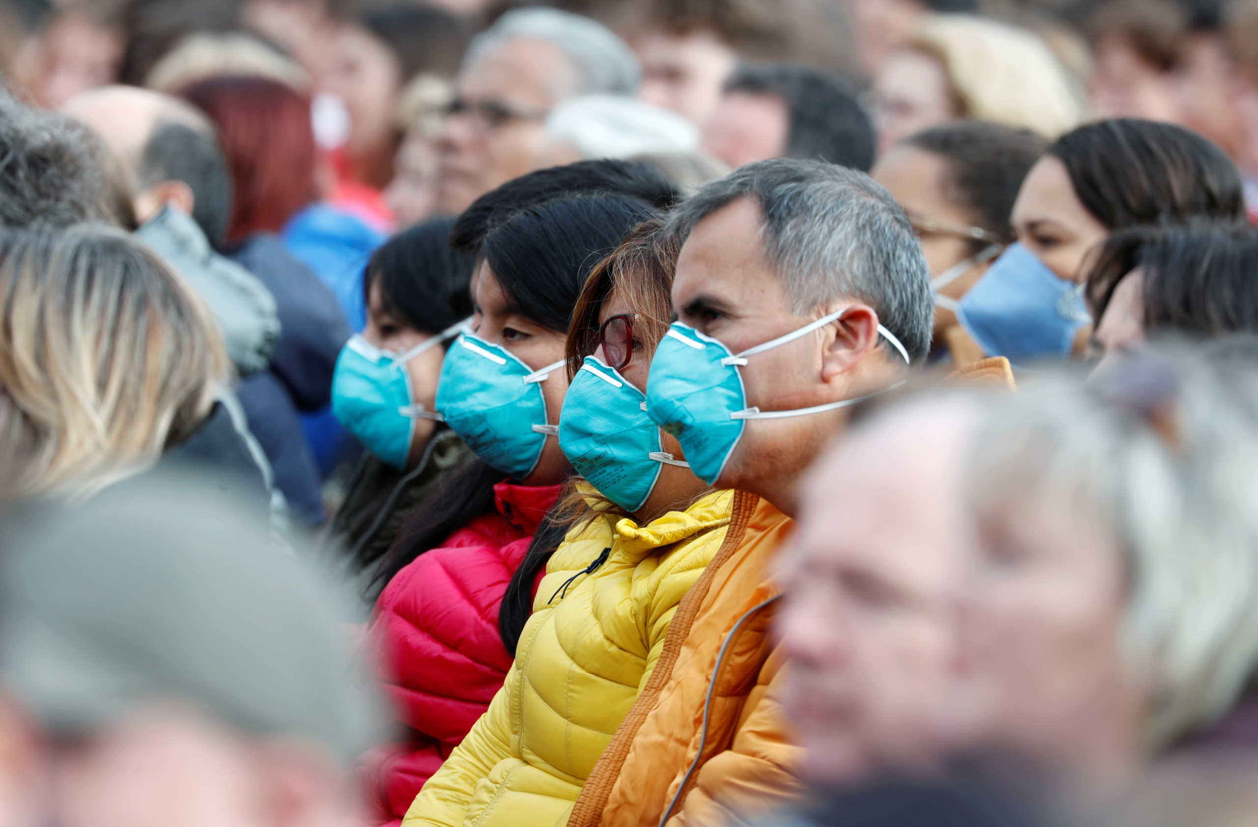 Faithful in face masks wait for Pope Francis to arrive for the weekly general audience at the Vatican February 26, 2020. REUTERS