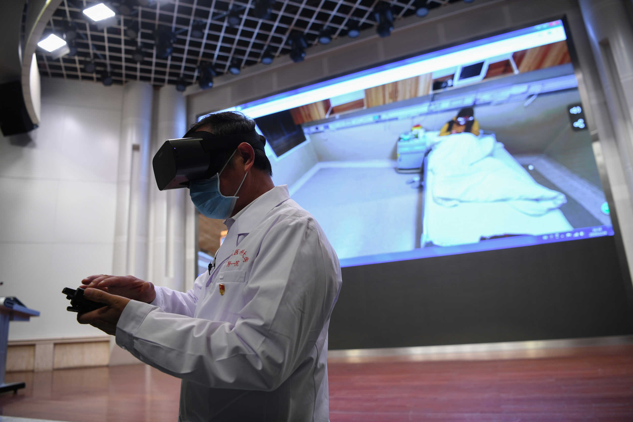 A medical staff wearing a virtual reality (VR) goggles checks a patient remotely at a hospital, following an outbreak of the novel coronavirus in the country, in Kunming, Yunnan province, China February 24, 2020. Picture taken February 24, 2020. cnsphoto via REUTERS. ATTENTION EDITORS - THIS IMAGE WAS PROVIDED BY A THIRD PARTY. CHINA OUT.