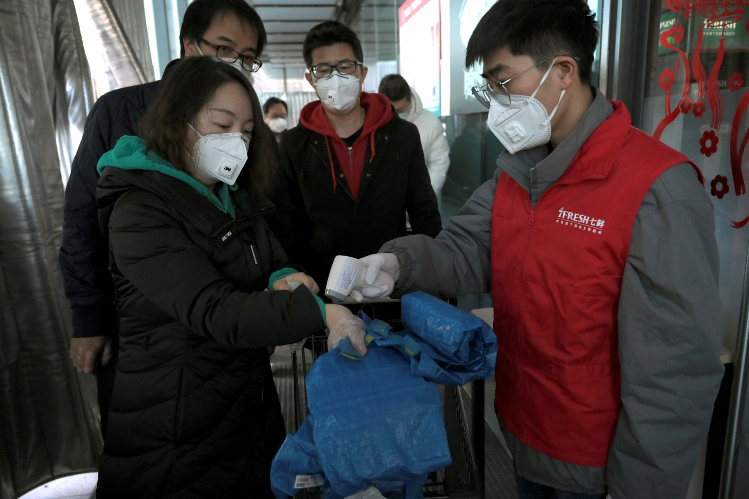 A staff member wearing a face mask checks temperature of customers entering a JD.com's 7Fresh chain, as the country is hit by an outbreak of the novel coronavirus, in Yizhuang town, Beijing, China February 8, 2020. Picture taken February 8, 2020. REUTERS