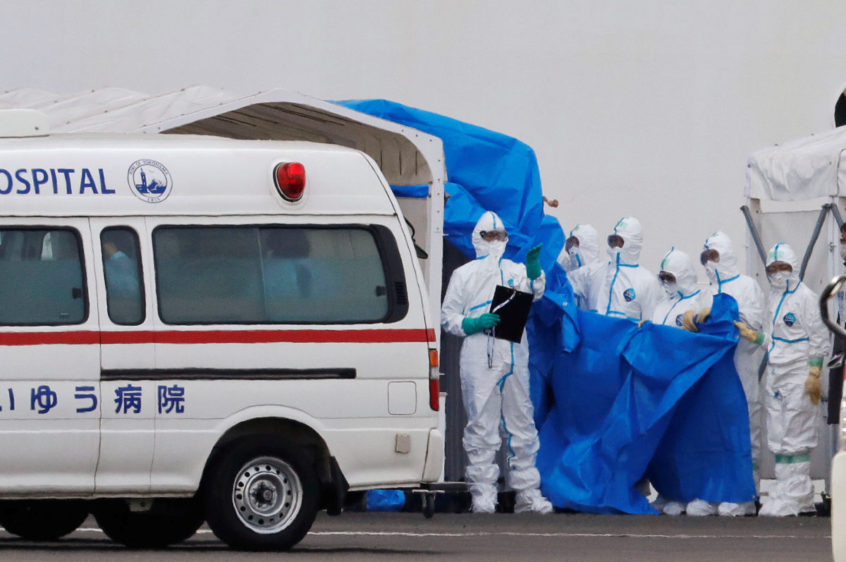 Workers wearing protective gear prepare to transfer passengers who tested positive for coronavirus from the cruise ship Diamond Princess to an ambulance bound for the hospital, at Daikoku Pier Cruise Terminal in Yokohama, south of Tokyo, Japan February 7, 2020. REUTERS