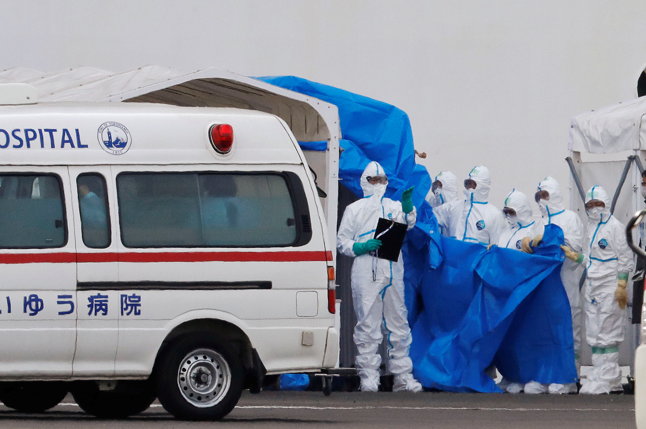 Workers wearing protective gear prepare to transfer passengers who tested positive for coronavirus from the cruise ship Diamond Princess to an ambulance bound for the hospital, at Daikoku Pier Cruise Terminal in Yokohama, south of Tokyo, Japan February 7, 2020. REUTERS