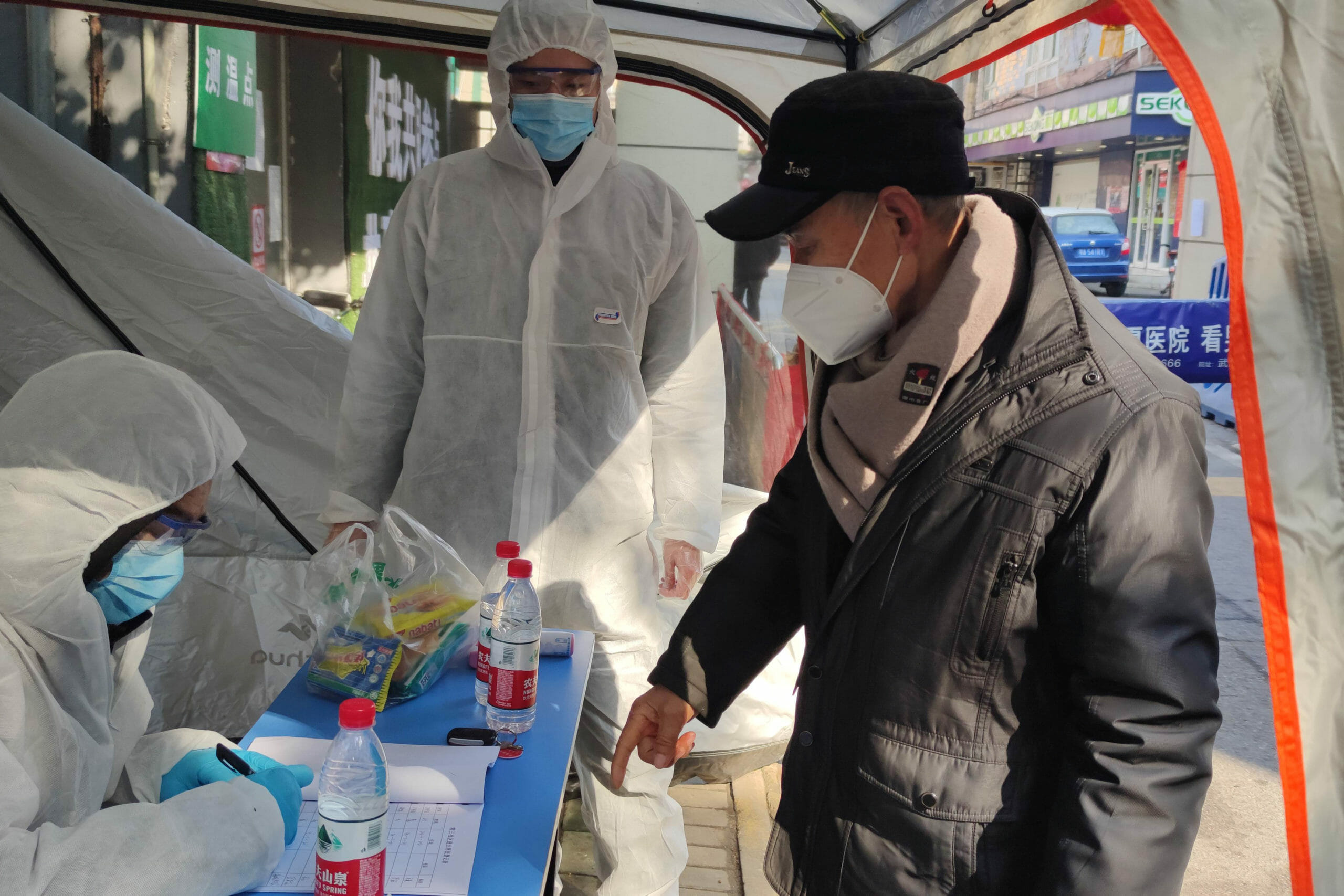 Volunteers in protective suits help a man with registration at a checkpoint of a residential compound, following the outbreak of the novel coronavirus in Wuhan, Hubei province, China February 9, 2020. Picture taken February 9, 2020. China Daily via REUTERS  ATTENTION EDITORS - THIS IMAGE WAS PROVIDED BY A THIRD PARTY. CHINA OUT.