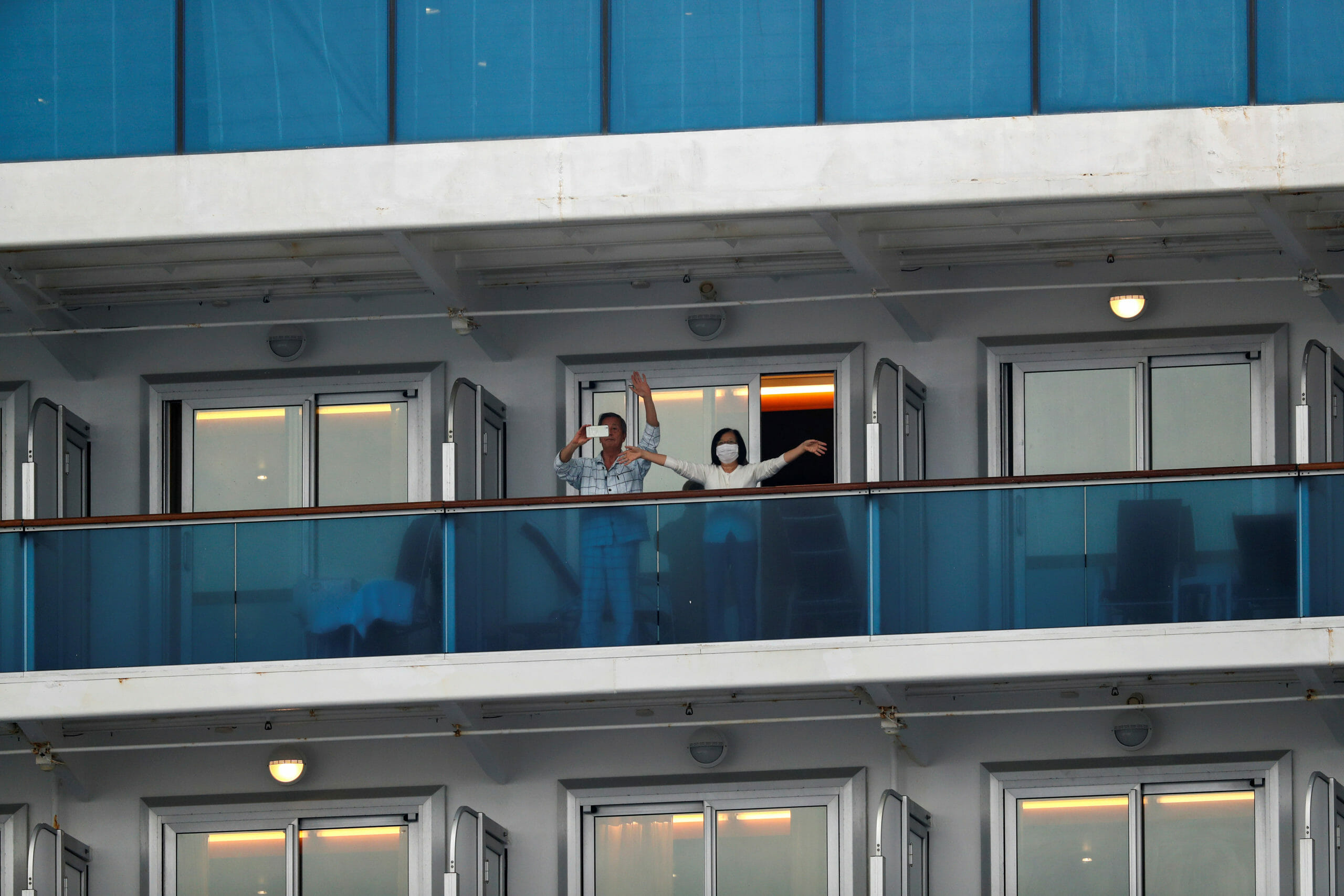 Passengers wave on the cruise ship Diamond Princess, as the vessel's passengers continue to be tested for coronavirus, at Daikoku Pier Cruise Terminal in Yokohama, south of Tokyo, Japan February 16, 2020. REUTERS