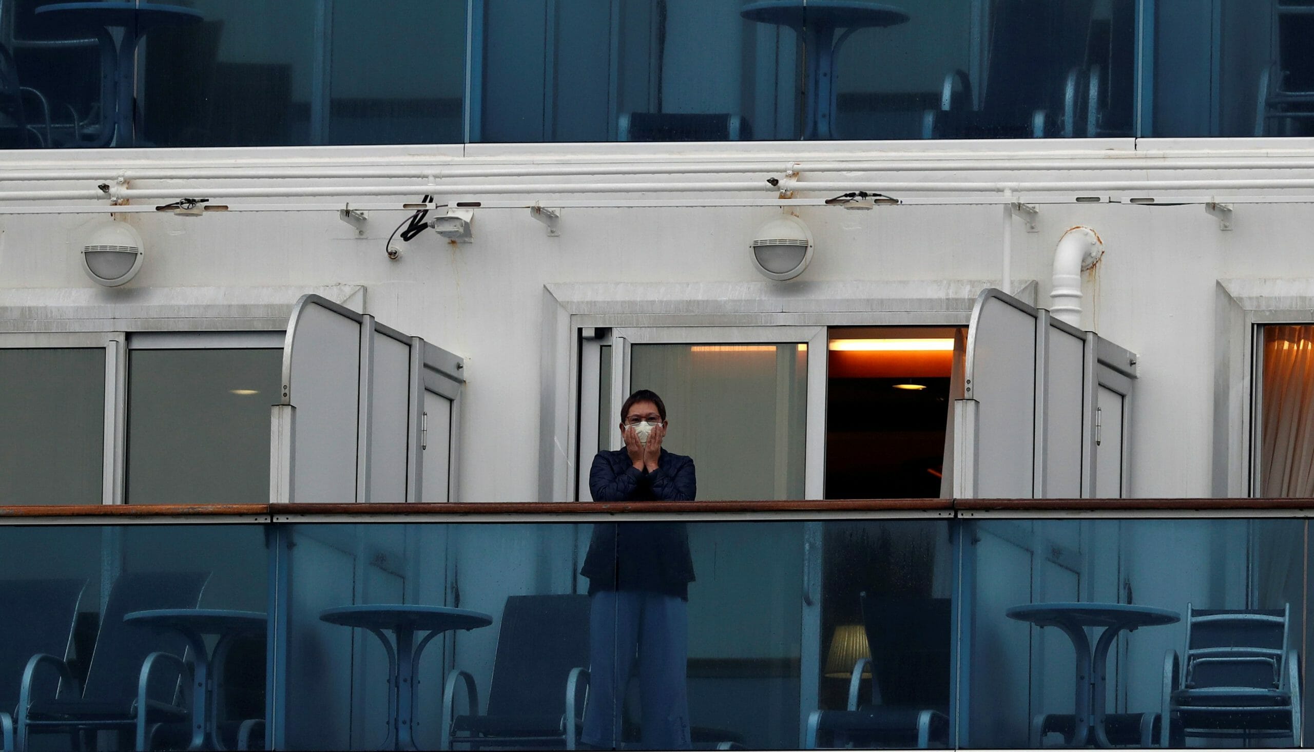 A passenger wearing a protective face mask is seen on the cruise ship Diamond Princess, as the vessel's passengers continue to be tested for coronavirus, at Daikoku Pier Cruise Terminal in Yokohama, south of Tokyo, Japan February 16, 2020. REUTERS