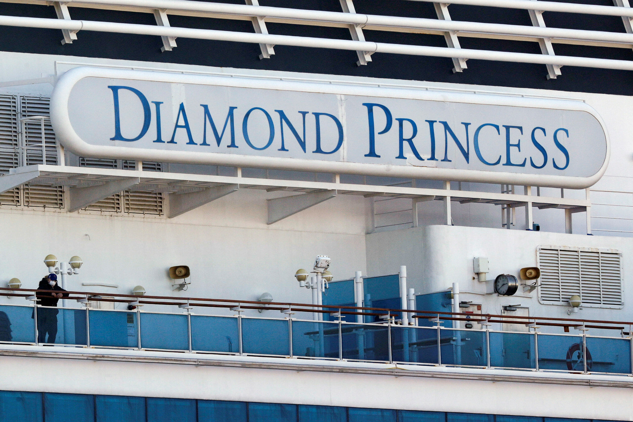 FILE PHOTO: A passenger wearing a mask stands on the deck of the cruise ship Diamond Princess, as the vessel's passengers continue to be tested for coronavirus, at Daikoku Pier Cruise Terminal in Yokohama, south of Tokyo, Japan February 13, 2020. REUTERS