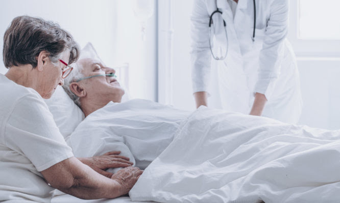 Doctor pronouncing death of an elderly patient in a presence of his spouse