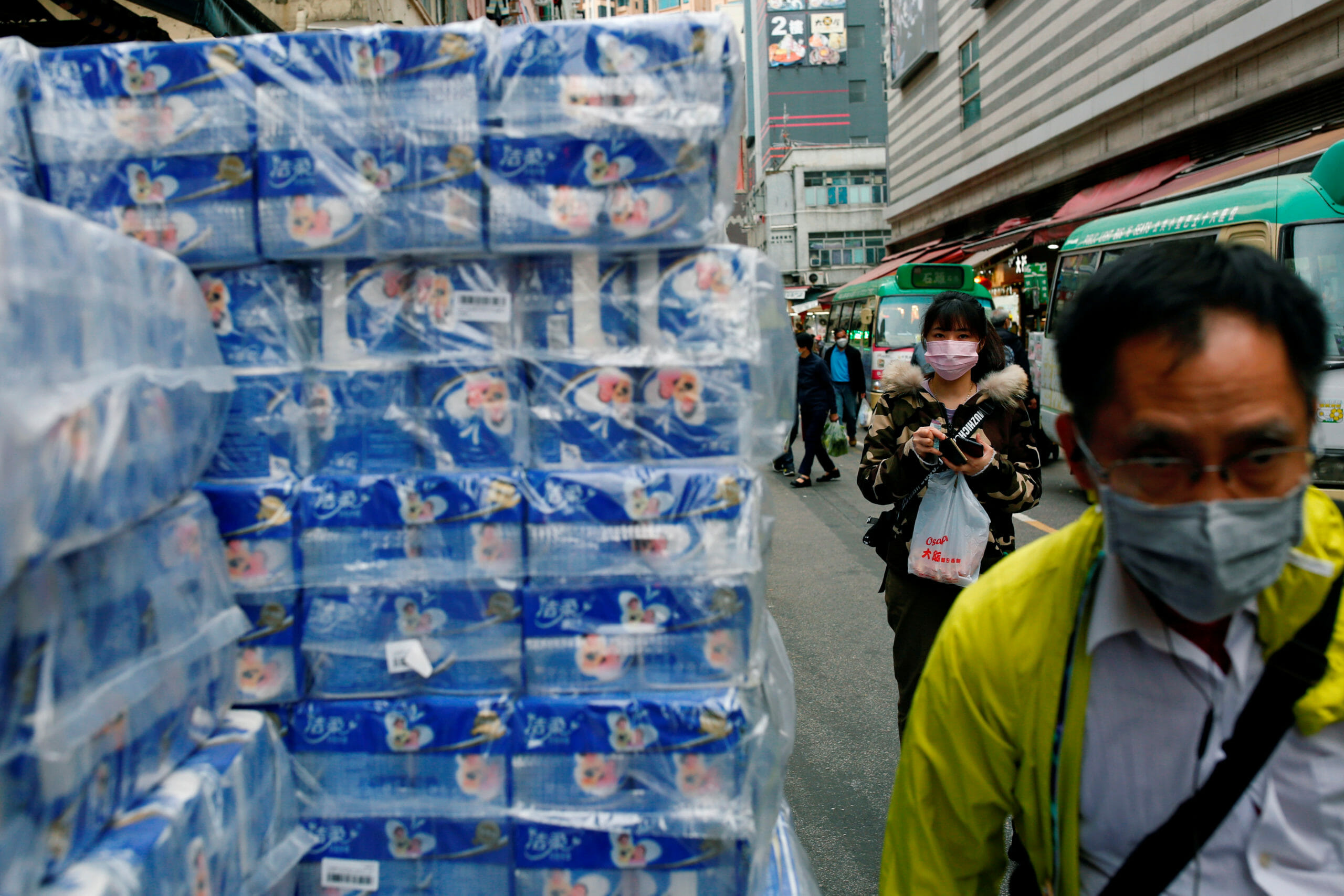 FILE PHOTO: People wear masks as they walk past rolls of toilet paper at a market, following the outbreak of a new coronavirus, in Hong Kong, China February 8, 2020. REUTERS