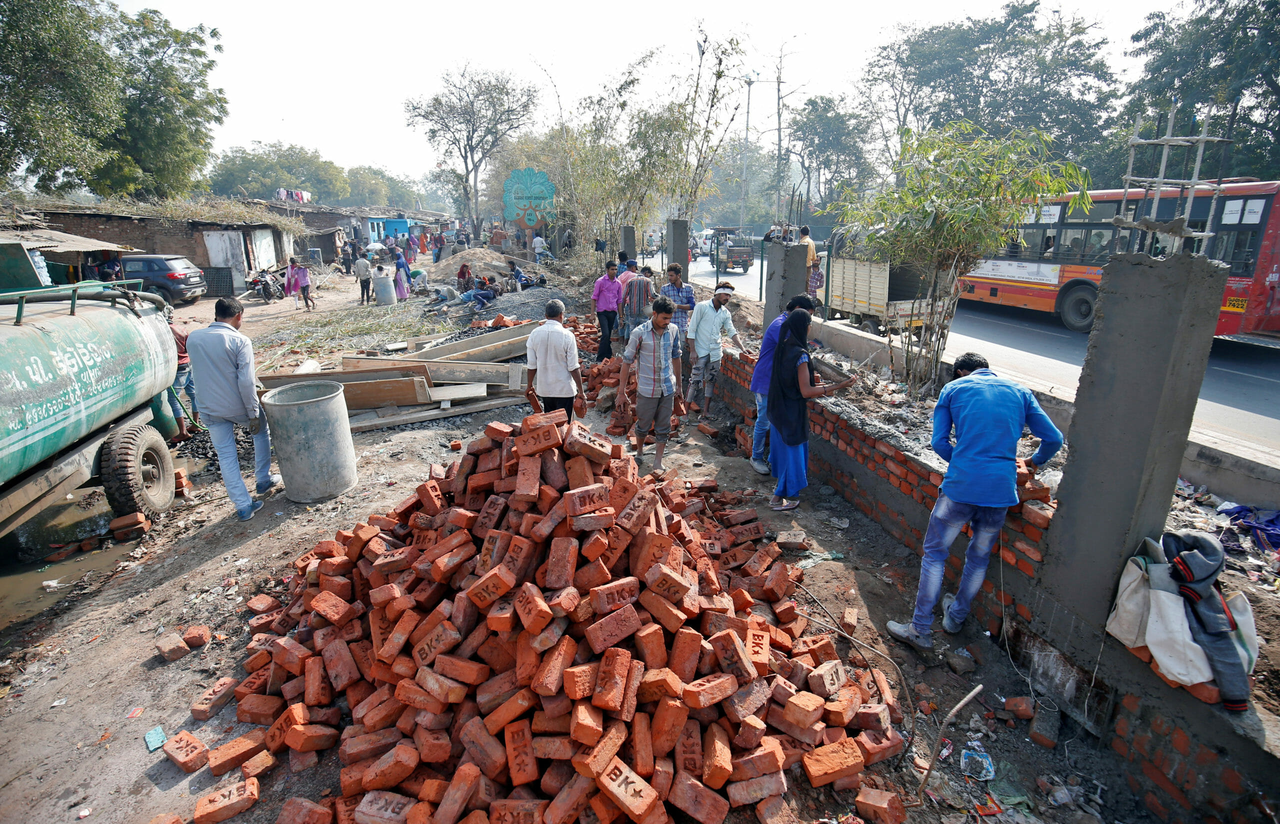 Construction workers build a wall along a slum area as part of a beautification drive along a route that U.S. President Donald Trump and India's Prime Minister Narendra Modi will be taking during Trump's visit later this month, in Ahmedabad, India, February 13, 2020. REUTERS