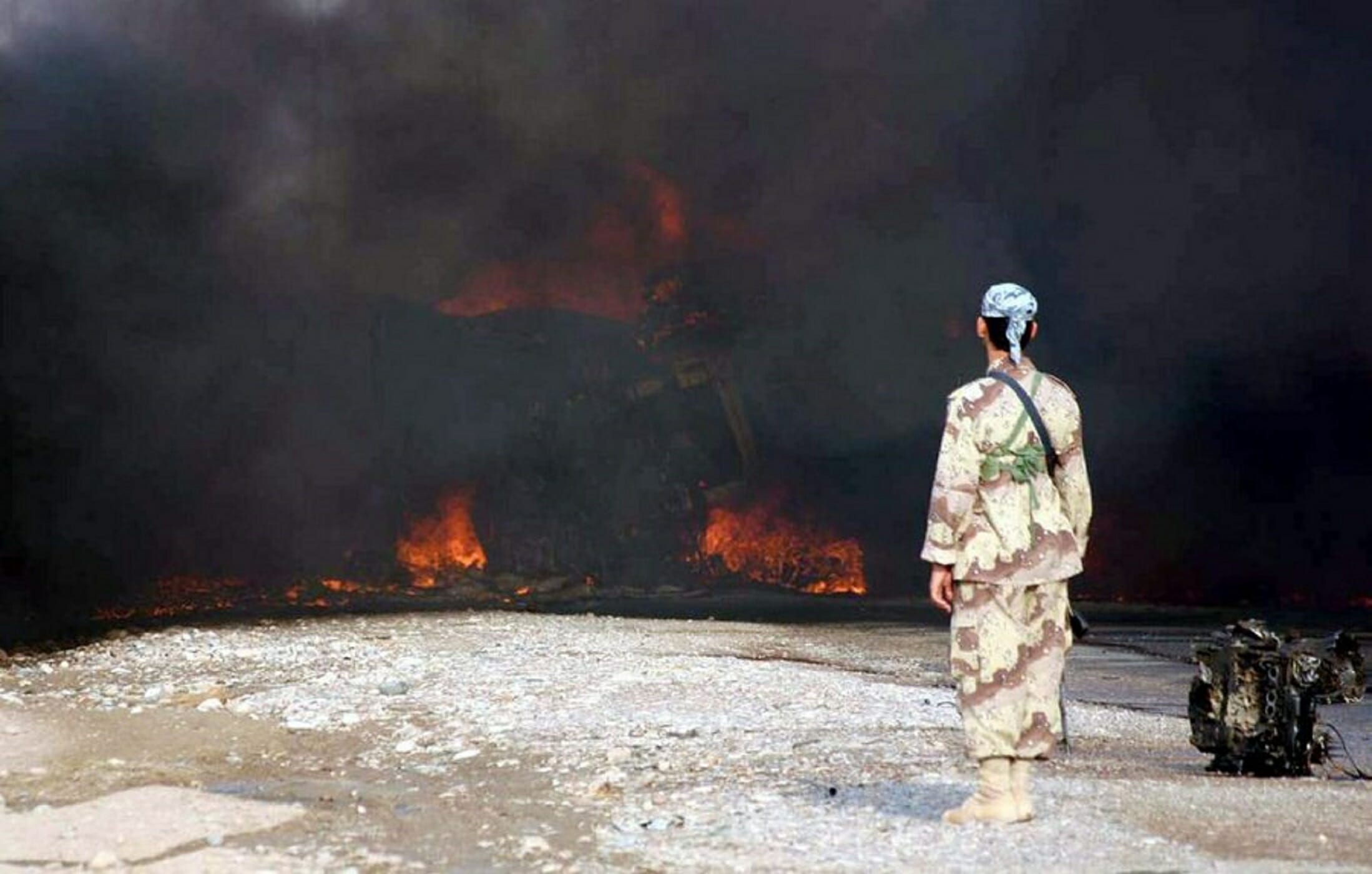 epa000301626 A soldier from Iraqi National Guards stands near to an exploded fuel truck in Baquba, Irak, Tuesday 26 October 2004.  EPA