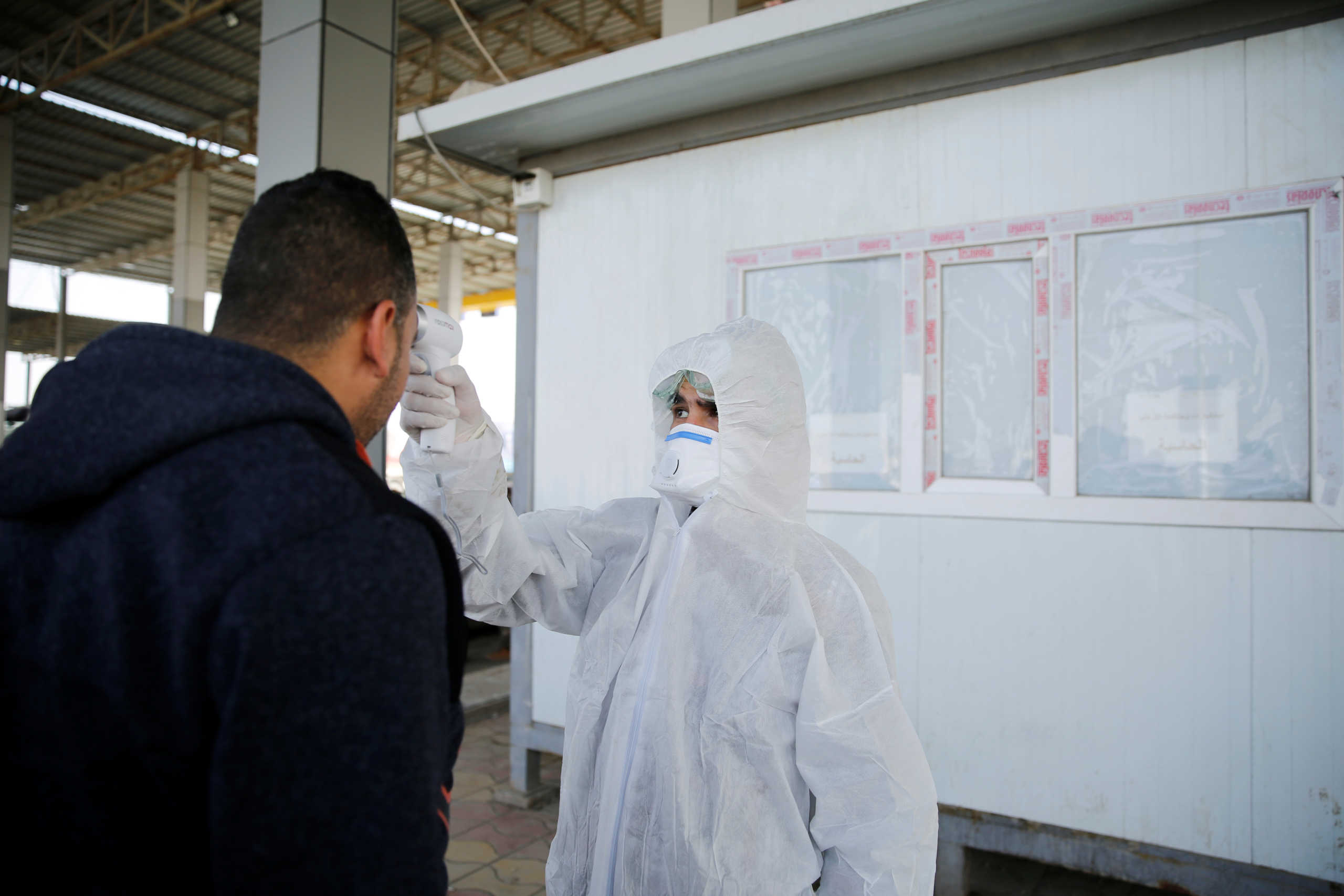 A member of the medical team checks the temperature of an Iraqi man, following the coronavirus outbreak, at the entrance checkpoint of South Mosul, Iraq February 26, 2020. REUTERS