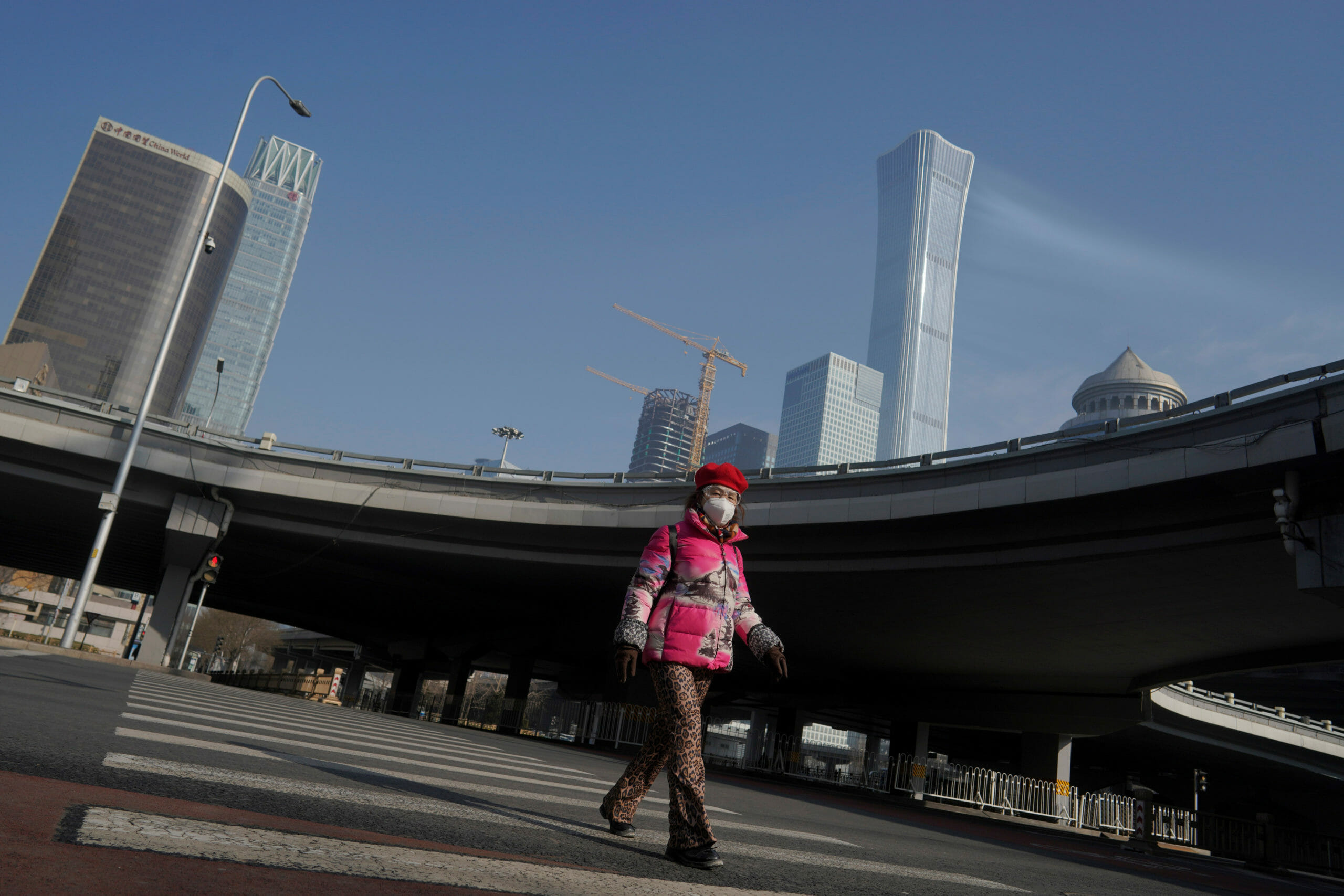 A woman wearing a face mask crosses a road after the extended Lunar New Year holiday caused by the novel coronavirus outbreak, in Beijing's central business district, China February 10, 2020. REUTERS
