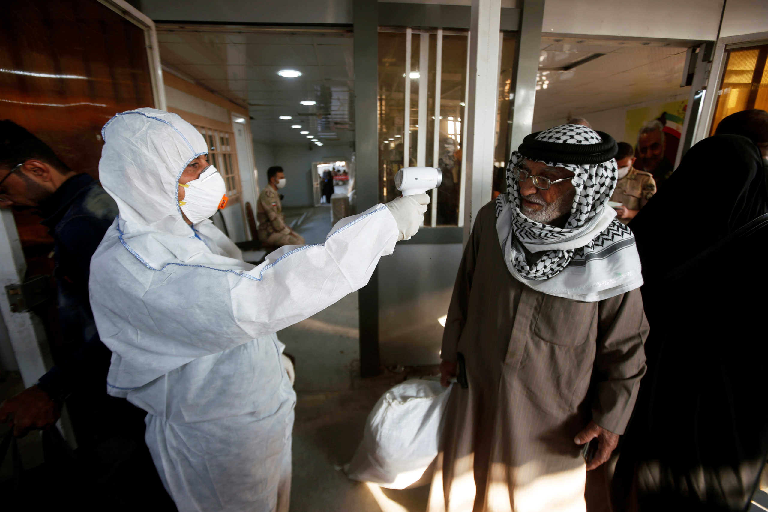 An Iraqi medical staff member checks a passenger's temperature, amid the new coronavirus outbreak, upon his arrival to Shalamcha Border Crossing between Iraq and Iran, February 20, 2020. REUTERS
