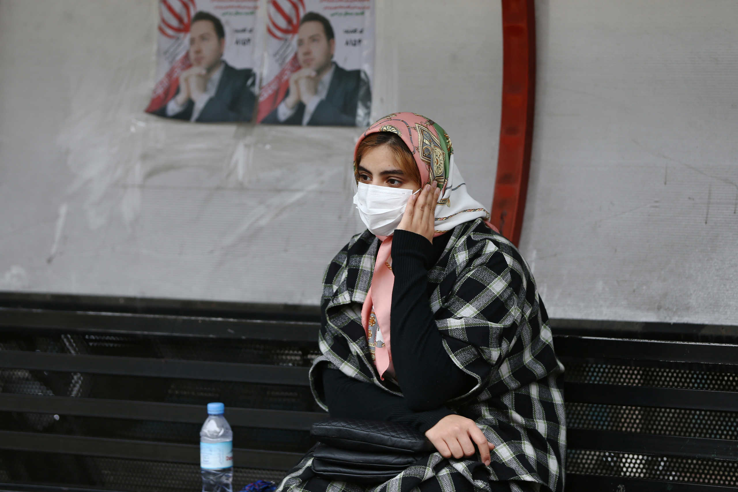 A woman sits near parliamentary election campaign posters in Tehran, Iran February 20, 2020. WANA (West Asia News Agency)