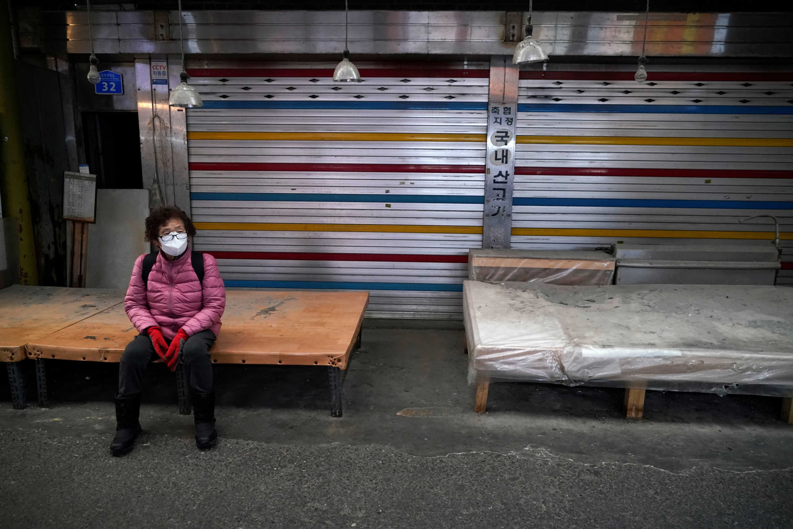 A woman wearing a mask to prevent contacting the coronavirus sits in front of a closed shop at a traditional market in Seoul, South Korea, February 24, 2020.   REUTERS