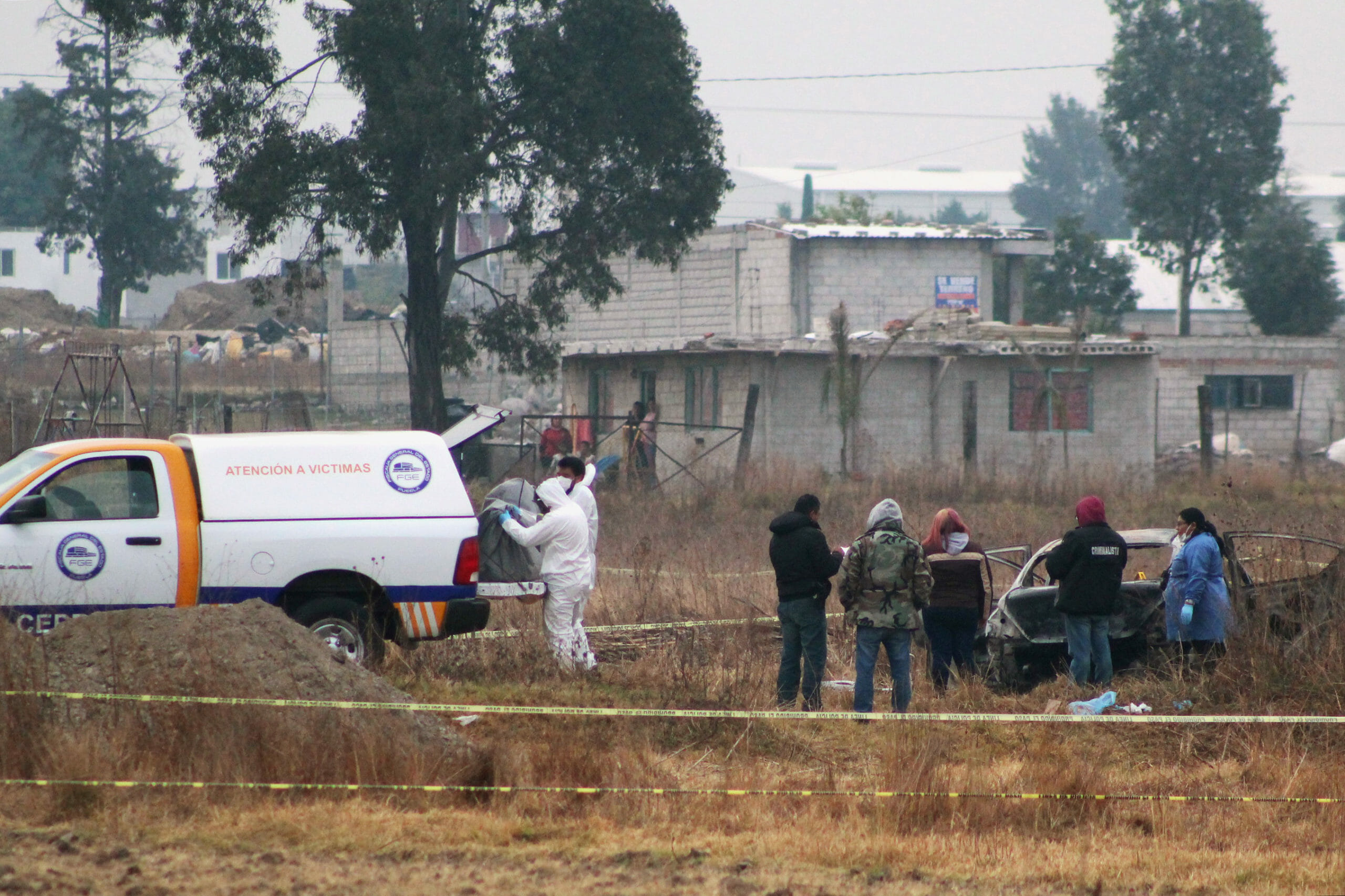 Forensic personnel carry a covered body at a crime scene where five burned bodies were found inside a vehicle (R), according to local media,  in San Lorenzo Almecatla, Mexico January 24, 2020. REUTERS