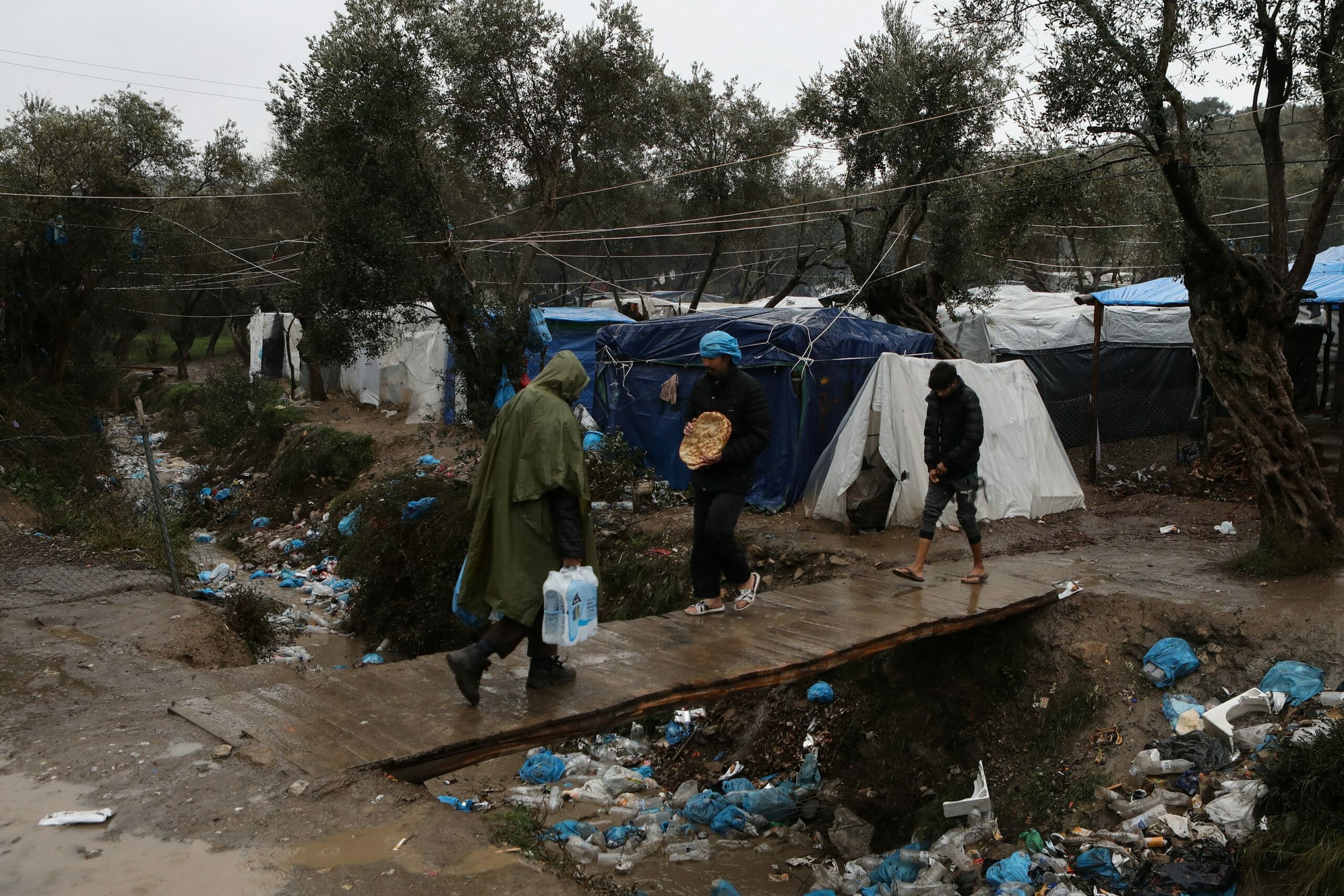 Migrants make their way during heavy rainfall at a temporary camp for refugees and migrants next to the Moria camp on the island of Lesbos, Greece, February 6, 2020. REUTERS