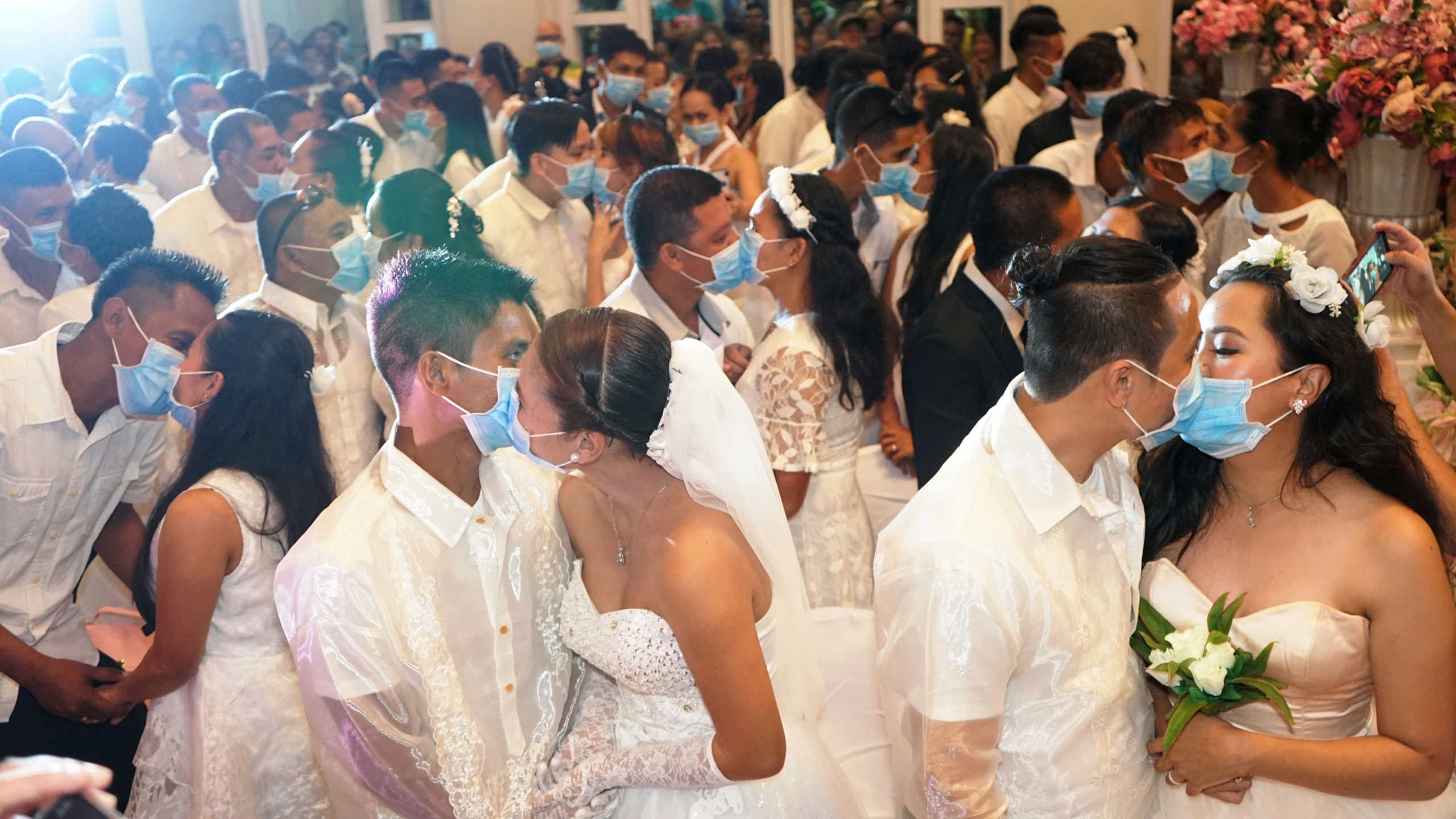Filipino couples kiss while wearing their face masks in a government-sponsored mass wedding in Bacolod City, Philippines, February 20, 2020. Picture taken February 20, 2020. Bacolod City Public Information Office
