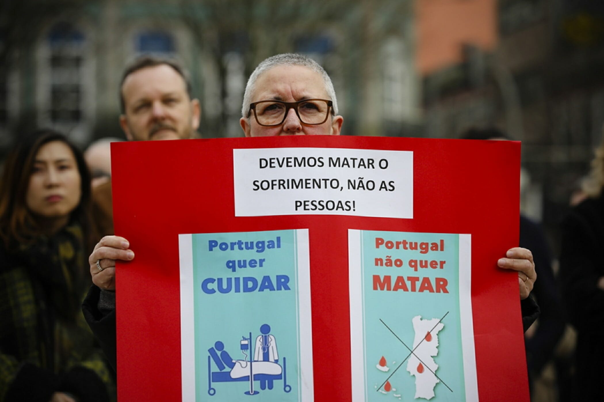 epa08220235 An anti-euthanasia protester belonging to the Simavida ('Yes to Life') Association poses as he holds up a placard reading in Portuguese: 'We have to kill suffering, not people!' in Porto, Portugal, 15 February 2020. The Portuguese parliament is set to debate a bill legalizing the practice of euthanasia (deliberately terminating a life to alleviate suffering) on 20 February 2020.  EPA