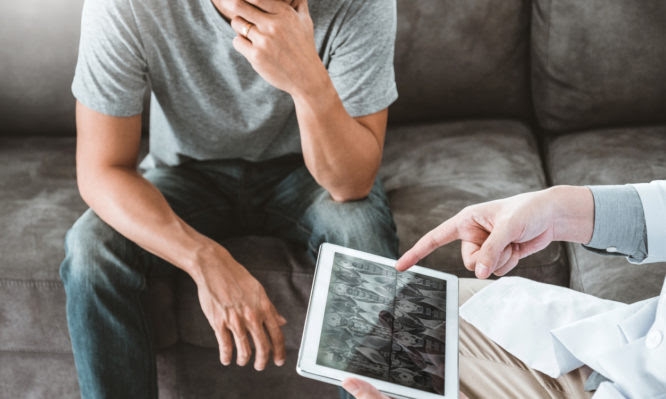 Doctor consulting diagnostic examining with patient presenting X-ray film results on digital tablet Visit the patient's home