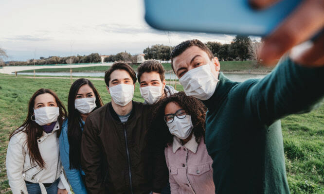 Group of six friends taking a selfie together while they are wearing protecting masks. Multi ethnic group of people wearing pollution masks to protect themselves from viruses.