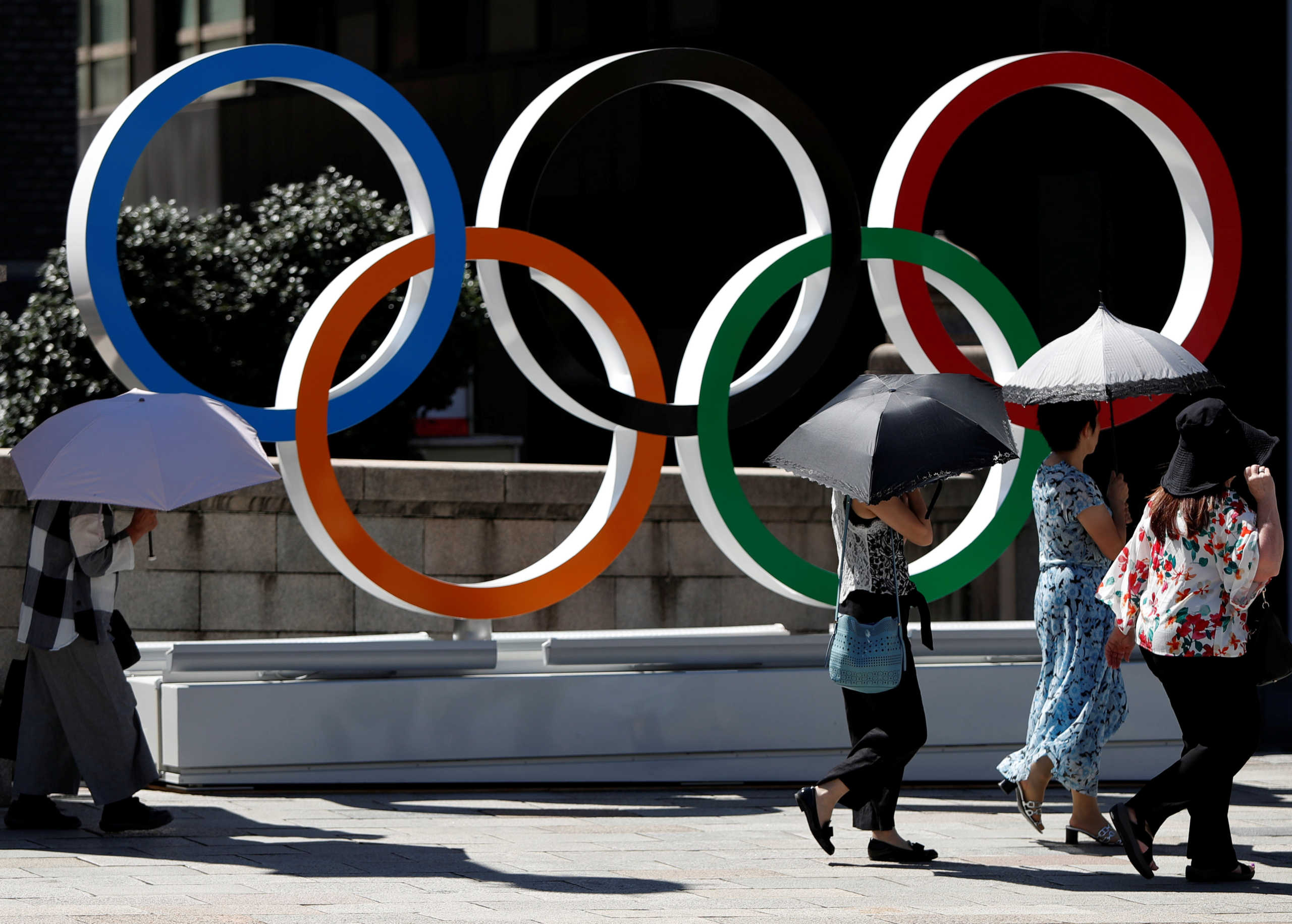 Passersby holding sunshades walk past Olympic rings displayed at Nihonbashi district in Tokyo, Japan August 5, 2019. Picture taken August 5, 2019.     REUTERS