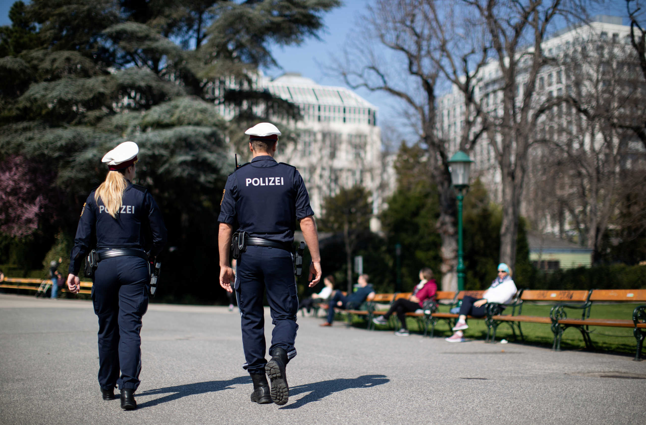 Police officers patrol Stadtpark as visitors keep social distance as they sit on park benches on a sunny spring day during the coronavirus disease (COVID-19) outbreak in Vienna, Austria March 20, 2020. REUTERS