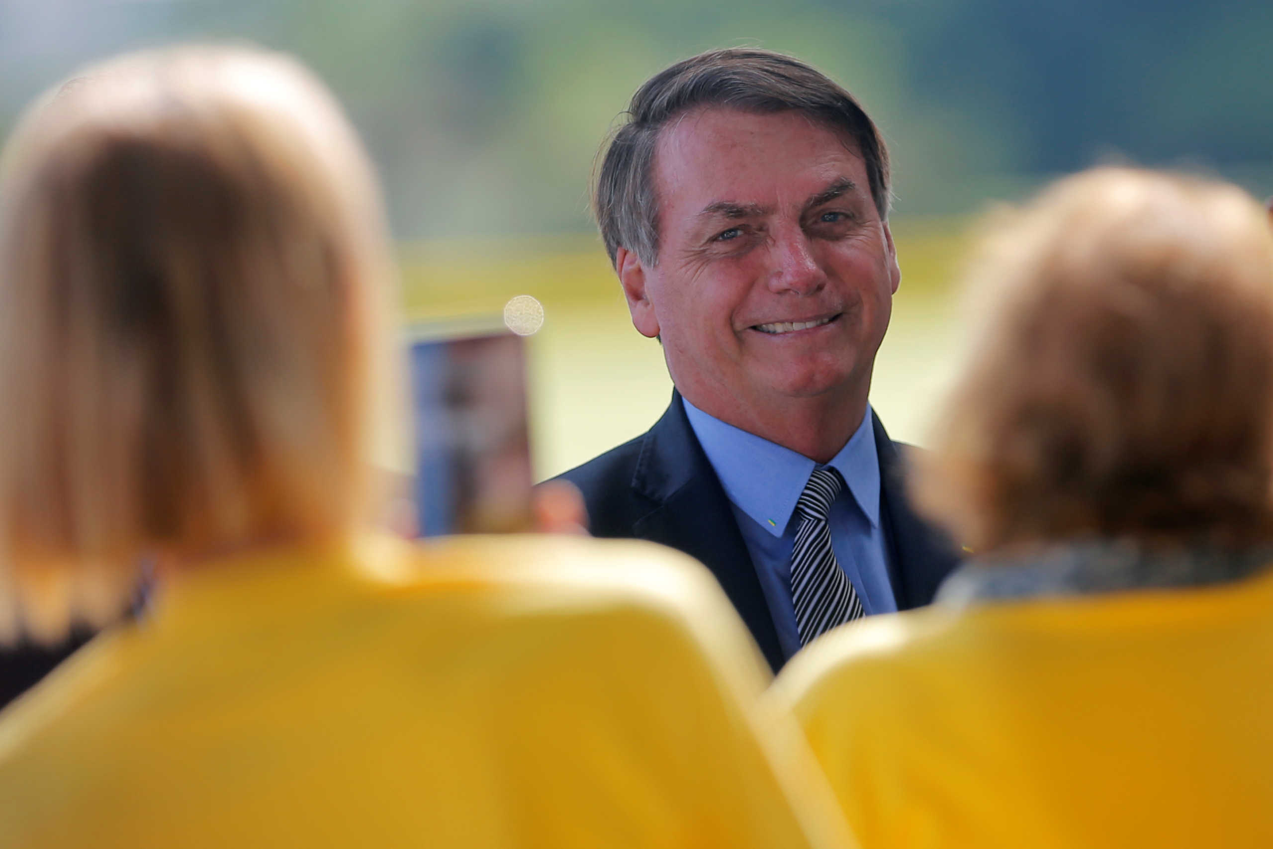 Brazil's President Jair Bolsonaro poses for pictures with supporters as he leaves Alvorada Palace in Brasilia, Brazil March 16, 2020. REUTERS