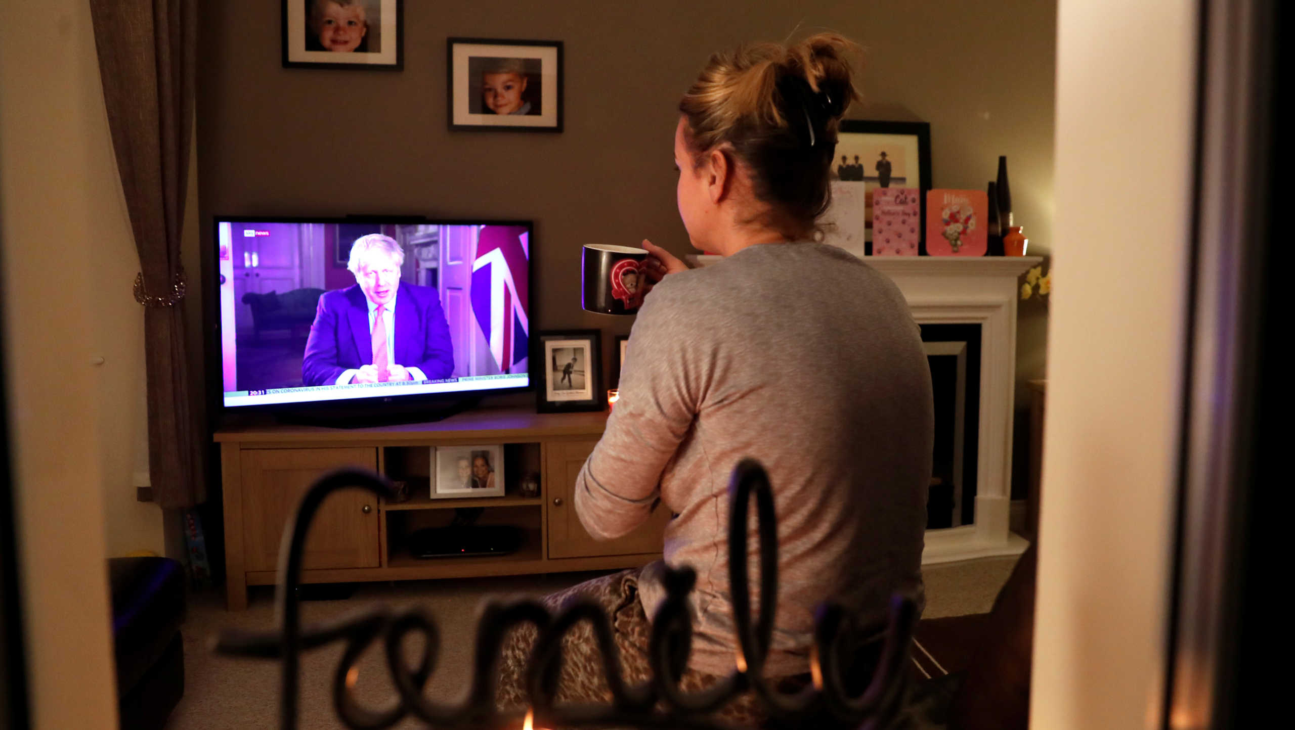 A woman watches British Prime Minister Boris Johnson's press conference as the spread of coronavirus disease (COVID-19) continues in Ouston, Britain March 23, 2020. REUTERS