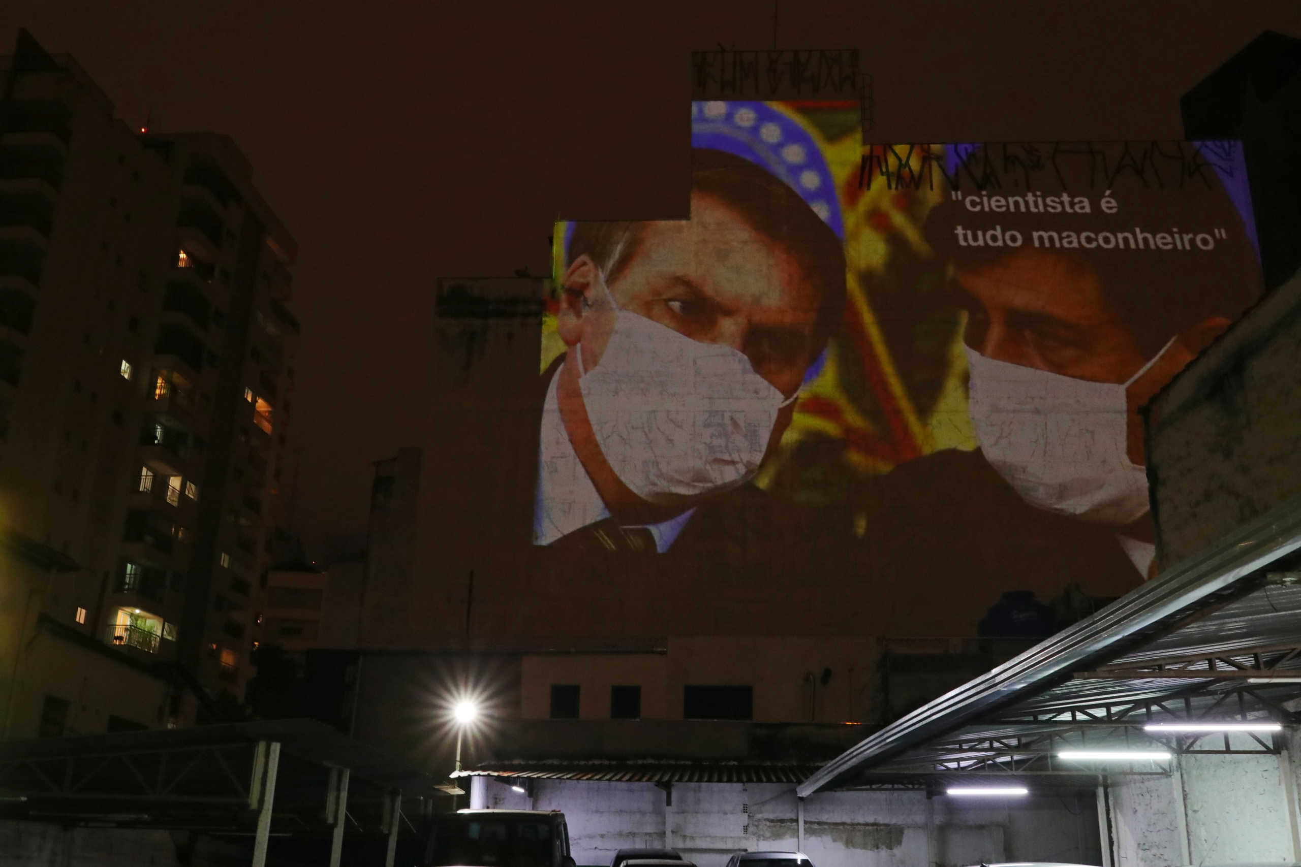 An image depicting Brazil's President Jair Bolsonaro and Health Minister Luiz Henrique Mandetta wearing protective face masks and the phrase “Scientists are all potheads” is projected on the wall of a building as a protest, following the coronavirus disease (COVID-19) outbreak in Sao Paulo, Brazil, March 19, 2020. REUTERS