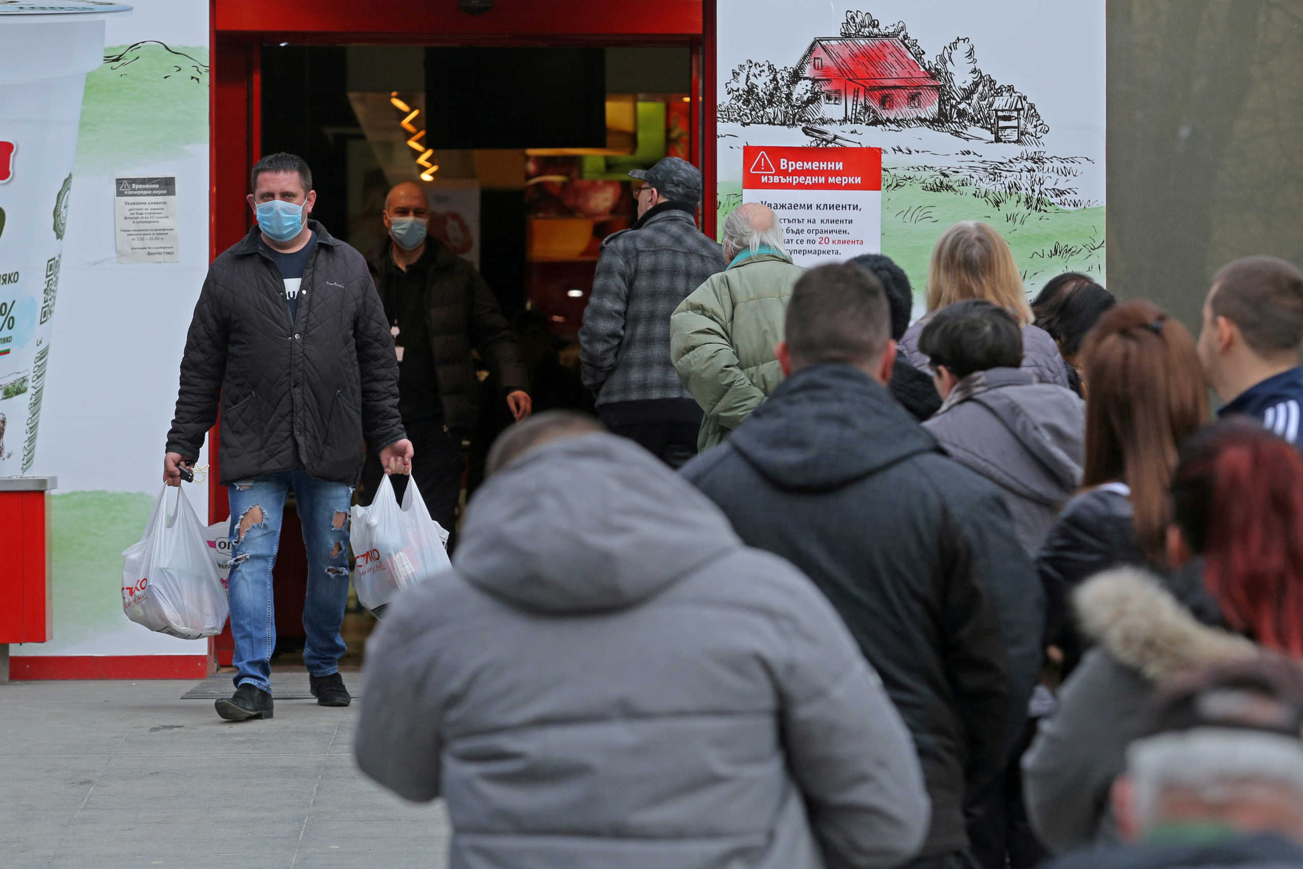 FILE PHOTO: A man with shopping bags walks out of a supermarket in front of a queue as shops need to observe emergency rules and make sure customers keep social distancing, due to coronavirus disease (COVID-19) outbreak, in Sofia, Bulgaria March 14, 2020. REUTERS