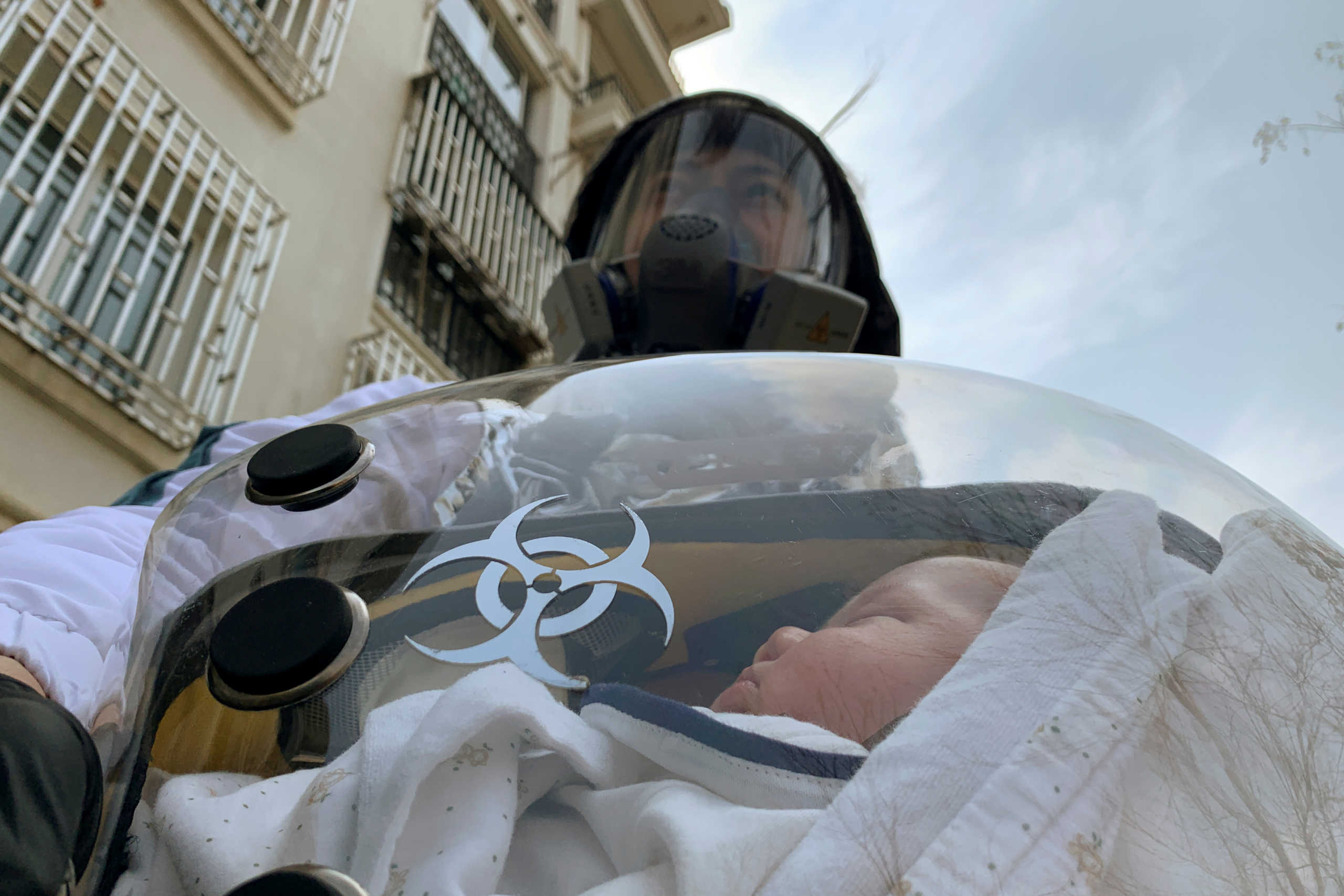 Cao Junjie poses for a picture with his two-month old baby inside a safety pod he created to protect his baby from the coronavirus disease (COVID-19), at a residential compound in Shanghai, China March 25, 2020. REUTERS