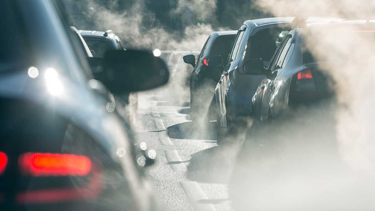Blurred silhouettes of cars surrounded by steam from the exhaust pipes. Traffic jam