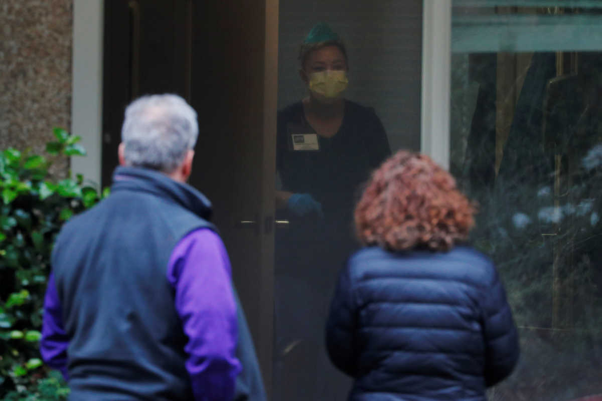 Steve Sedlacek and his sister Seri talk to a care giver while visiting their father Chuck, who is recovering from coronavirus disease (COVID-19) and is a resident at Life Care Center of Kirkland, in Kirkland, Washington, U.S., March 22, 2020.   REUTERS