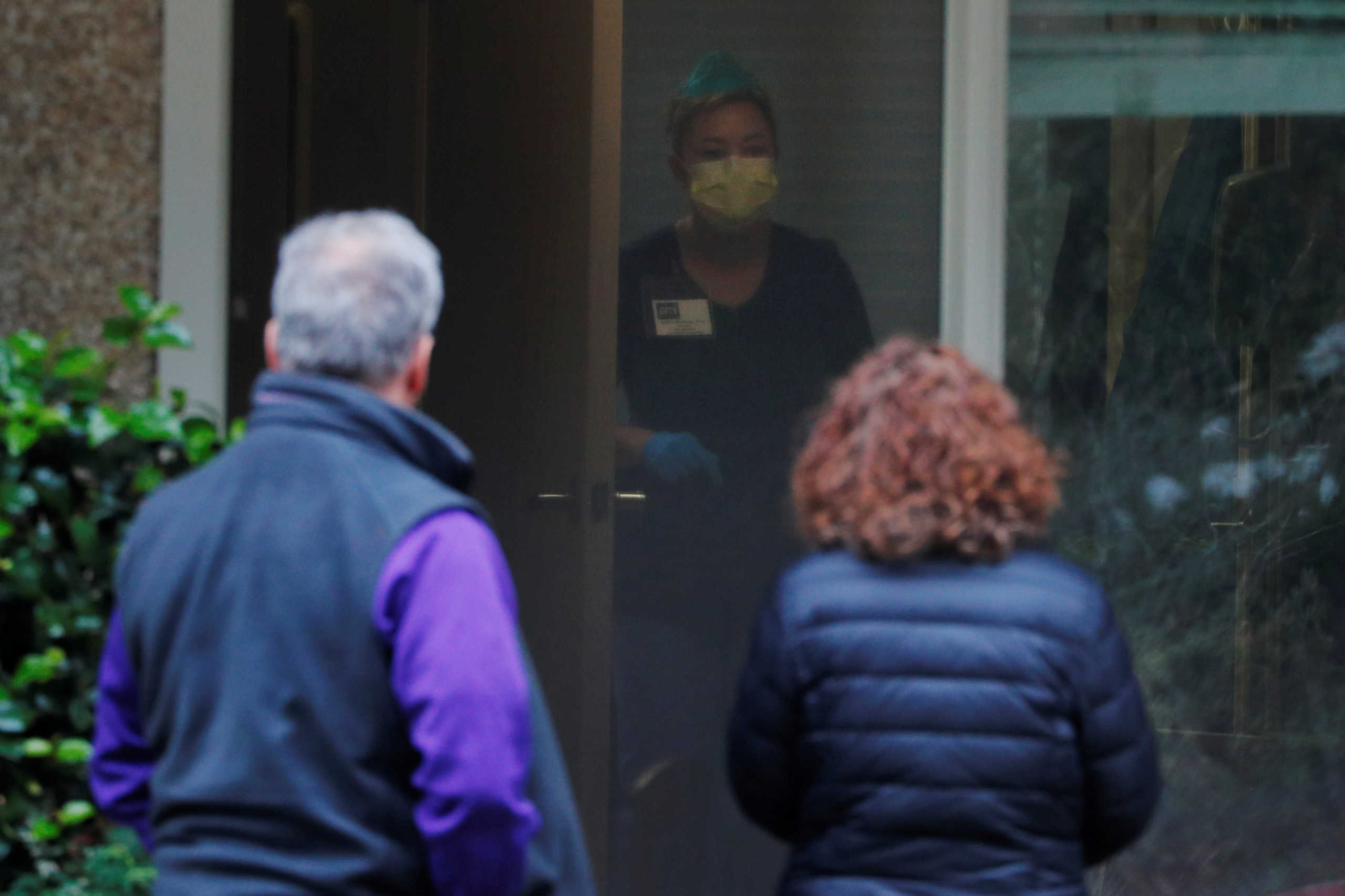 Steve Sedlacek and his sister Seri talk to a care giver while visiting their father Chuck, who is recovering from coronavirus disease (COVID-19) and is a resident at Life Care Center of Kirkland, in Kirkland, Washington, U.S., March 22, 2020.   REUTERS