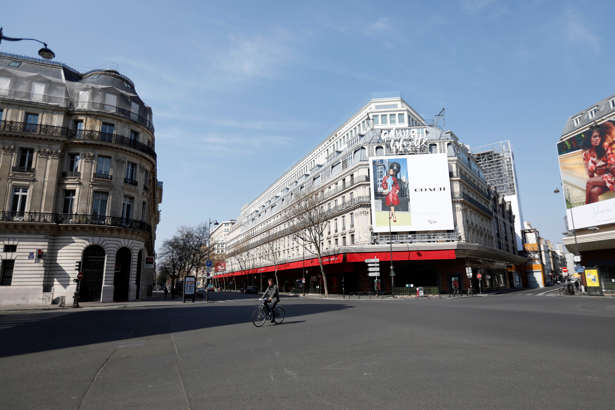 A cyclist rides in front of the deserted Galeries Lafayette department store in Paris as a lockdown is imposed to slow the rate of the coronavirus disease (COVID-19) in France, March 27, 2020. REUTERS